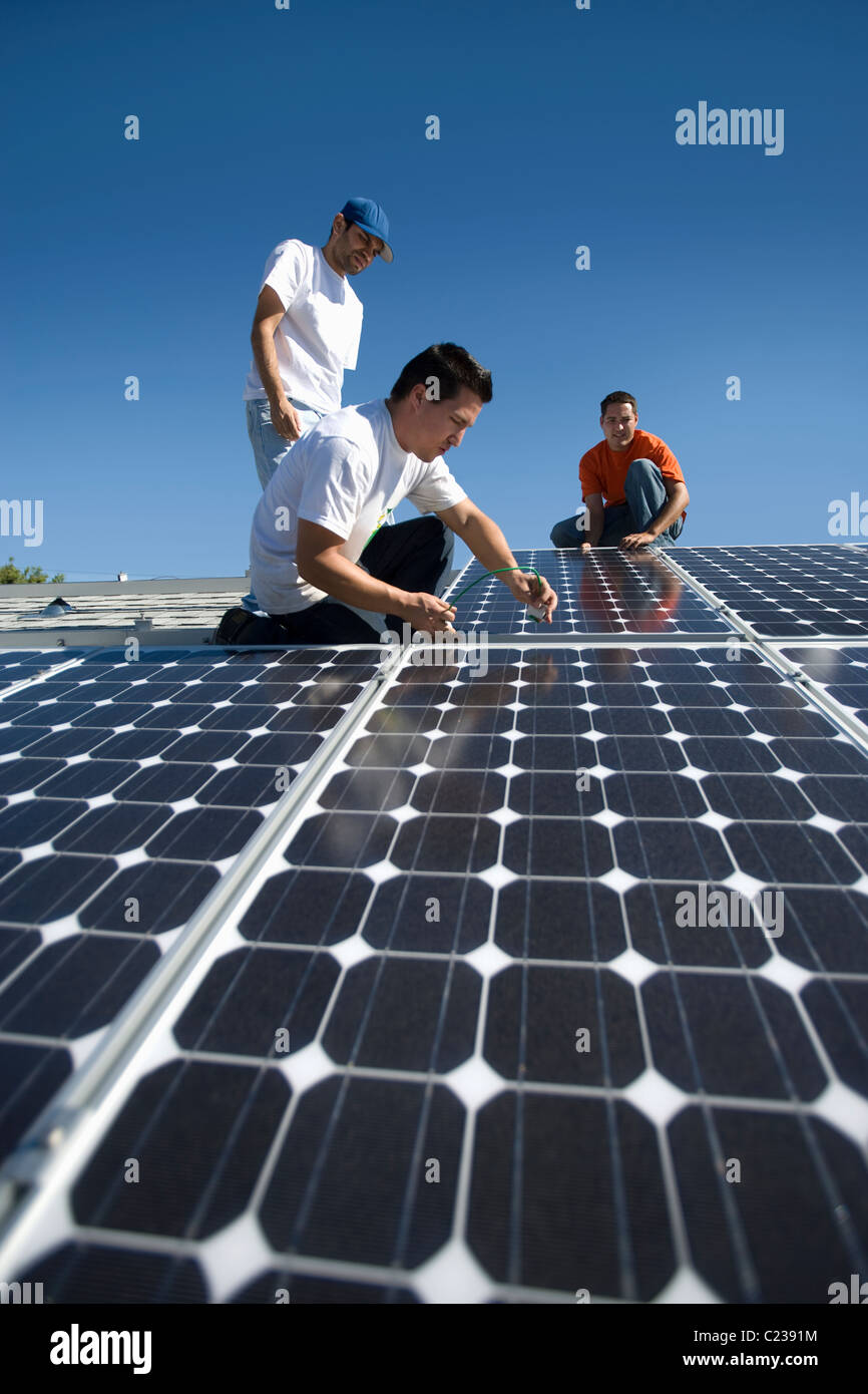 Un groupe d'hommes qui travaillent sur les panneaux solaires Banque D'Images