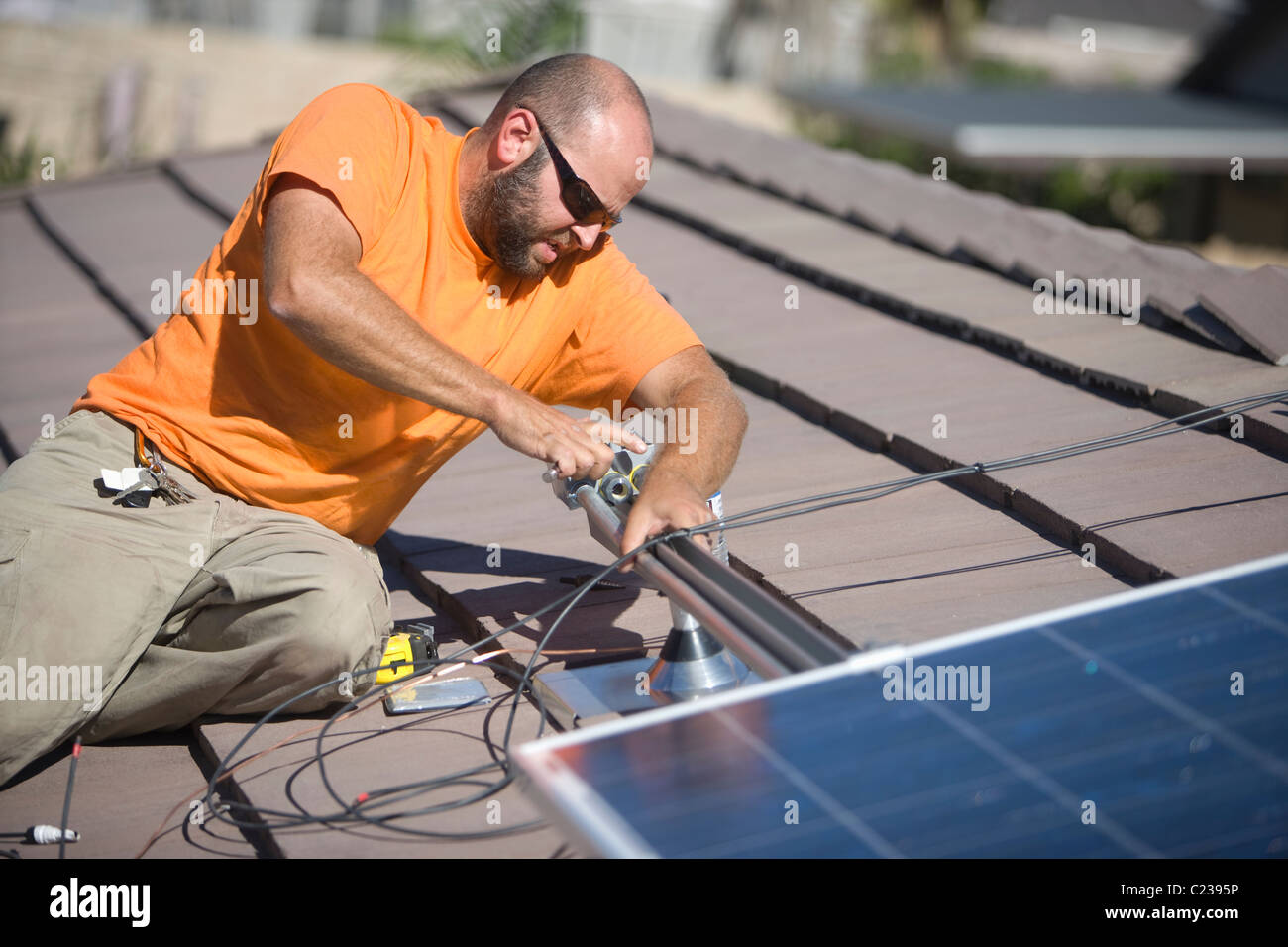Un homme travaillant sur panneaux solaires sur un toit haut Banque D'Images