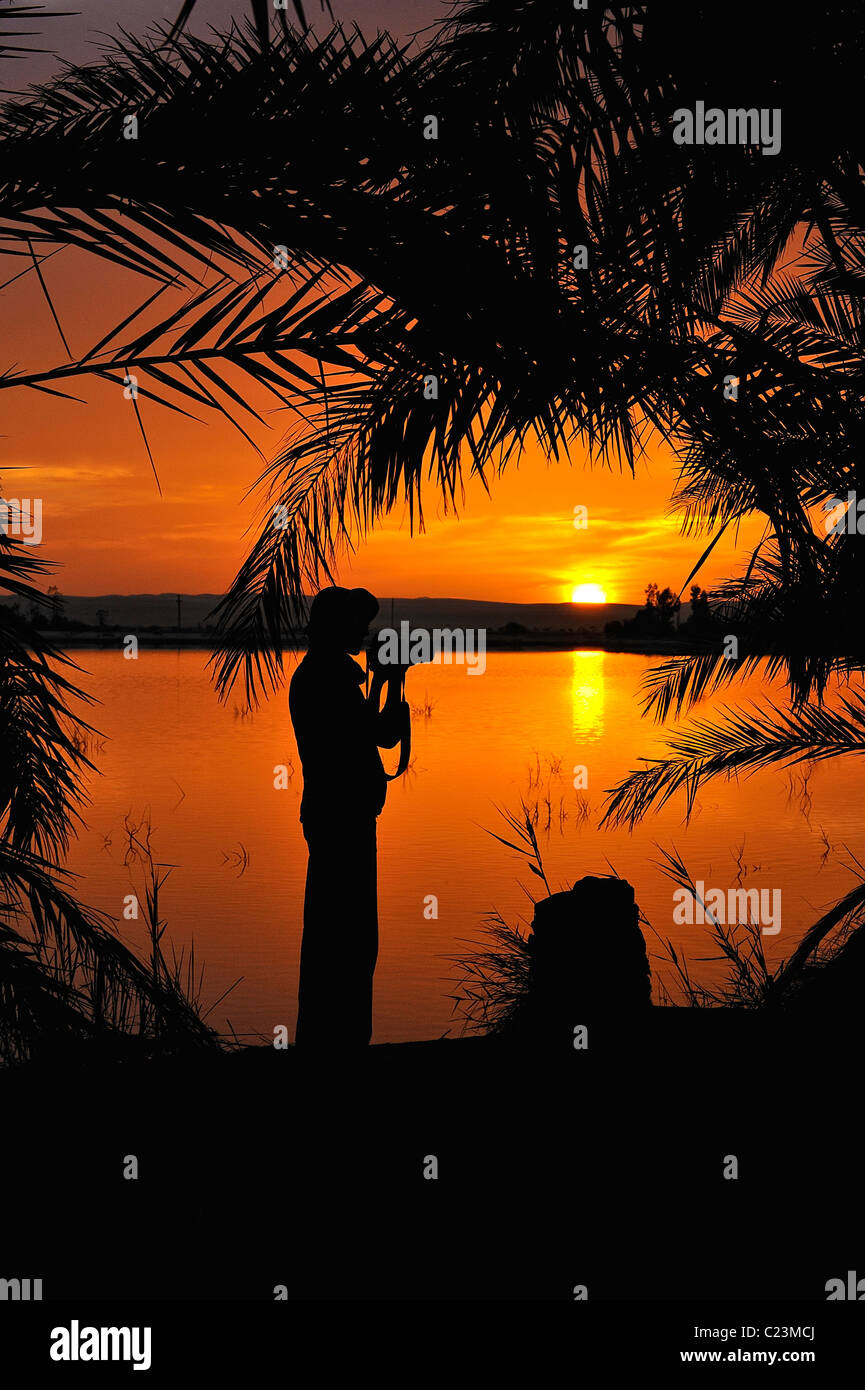 Silhouette de femme lors d'un coucher de soleil sur un lac salé à Fatnas Island près de la ville de Siwa, désert de l'ouest, l'Egypte Banque D'Images