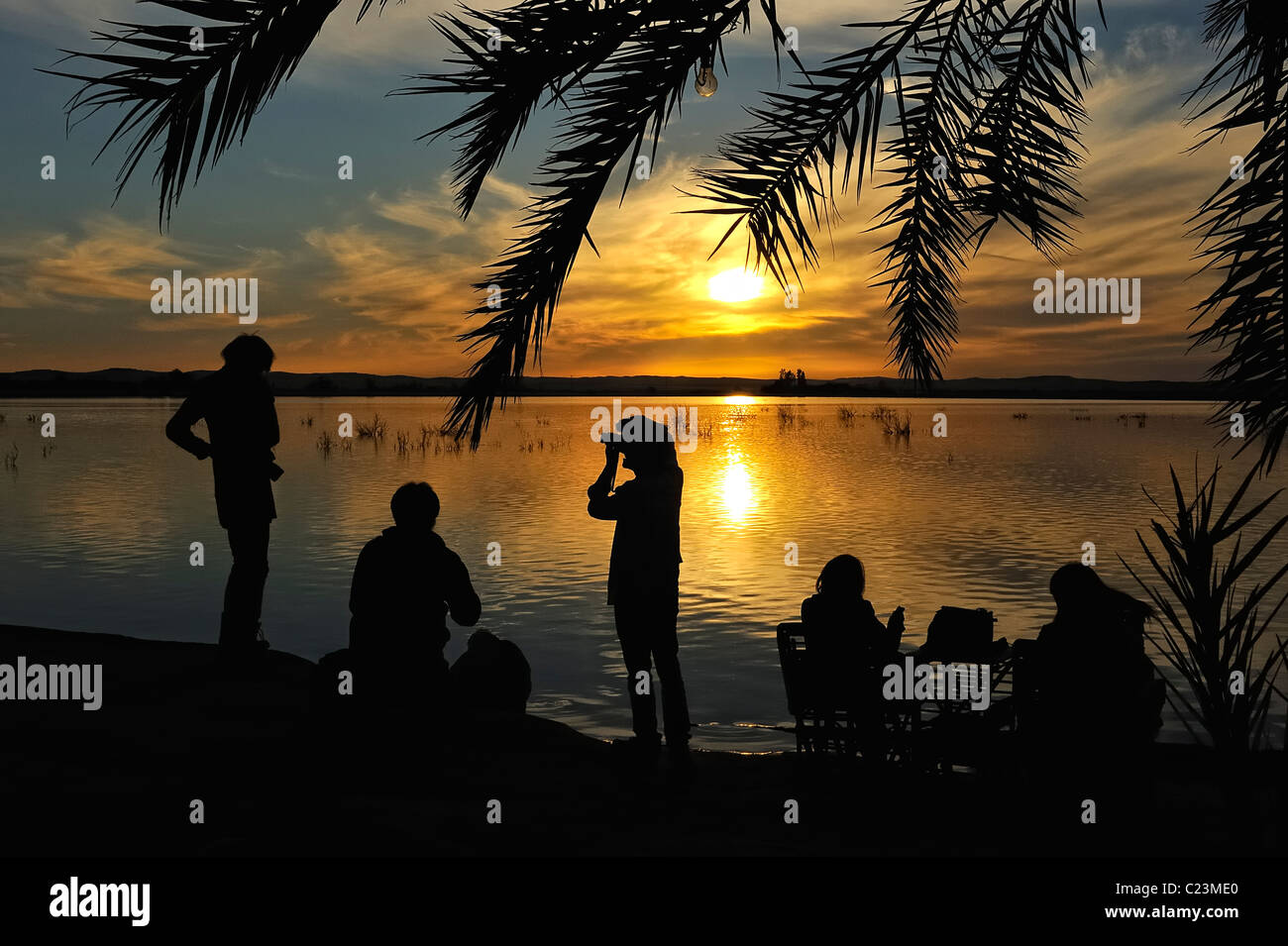 Silhouette d'un groupe de personnes lors d'un coucher de soleil sur un lac salé à Fatnas Island près de la ville de Siwa, désert de l'ouest, l'Egypte Banque D'Images