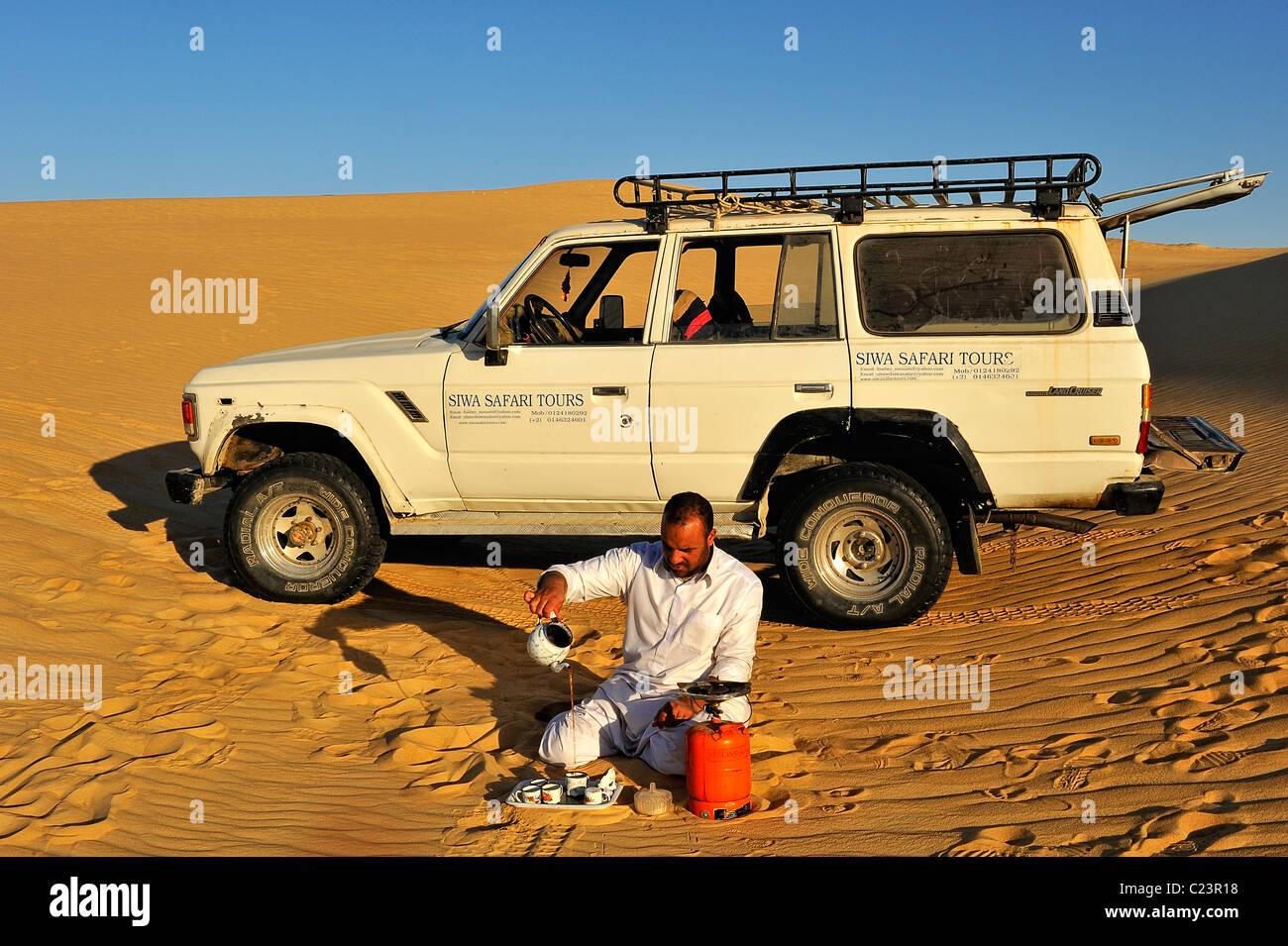 L'homme égyptien un plateau/près d'une voiture sur le sable dans la Grande Mer de Sable, Western Desert (désert de Libye), Égypte Banque D'Images