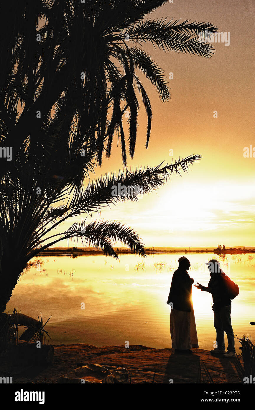 Deux Egyptiens durant un coucher de soleil sur un lac salé à Fatnas Island près de la ville de Siwa, désert de l'ouest, l'Egypte Banque D'Images