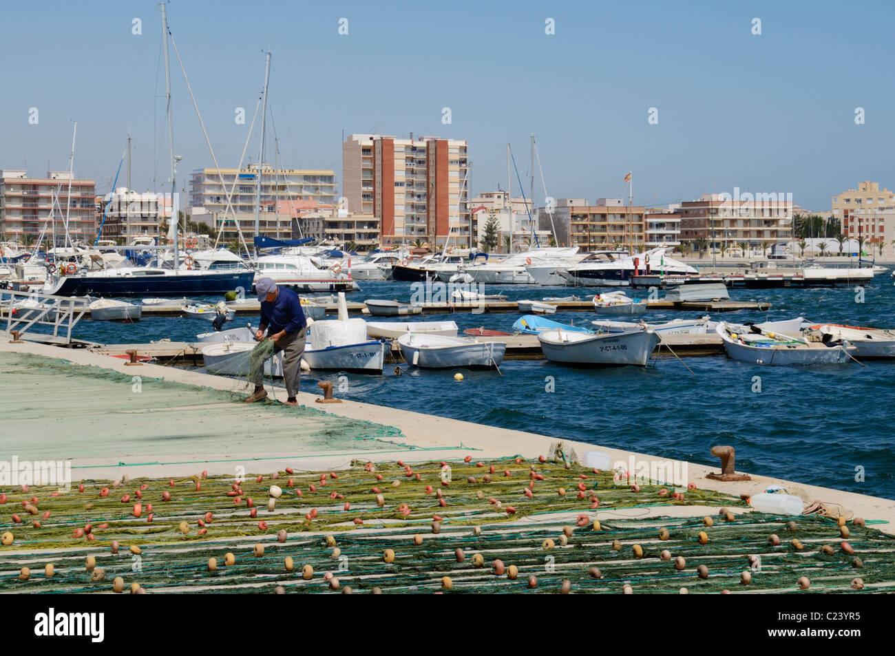Un pêcheur a tendance à ses filets sur le quai en Méditerranée port de San Pedro del Pinatar, Murcia, Espagne. Banque D'Images