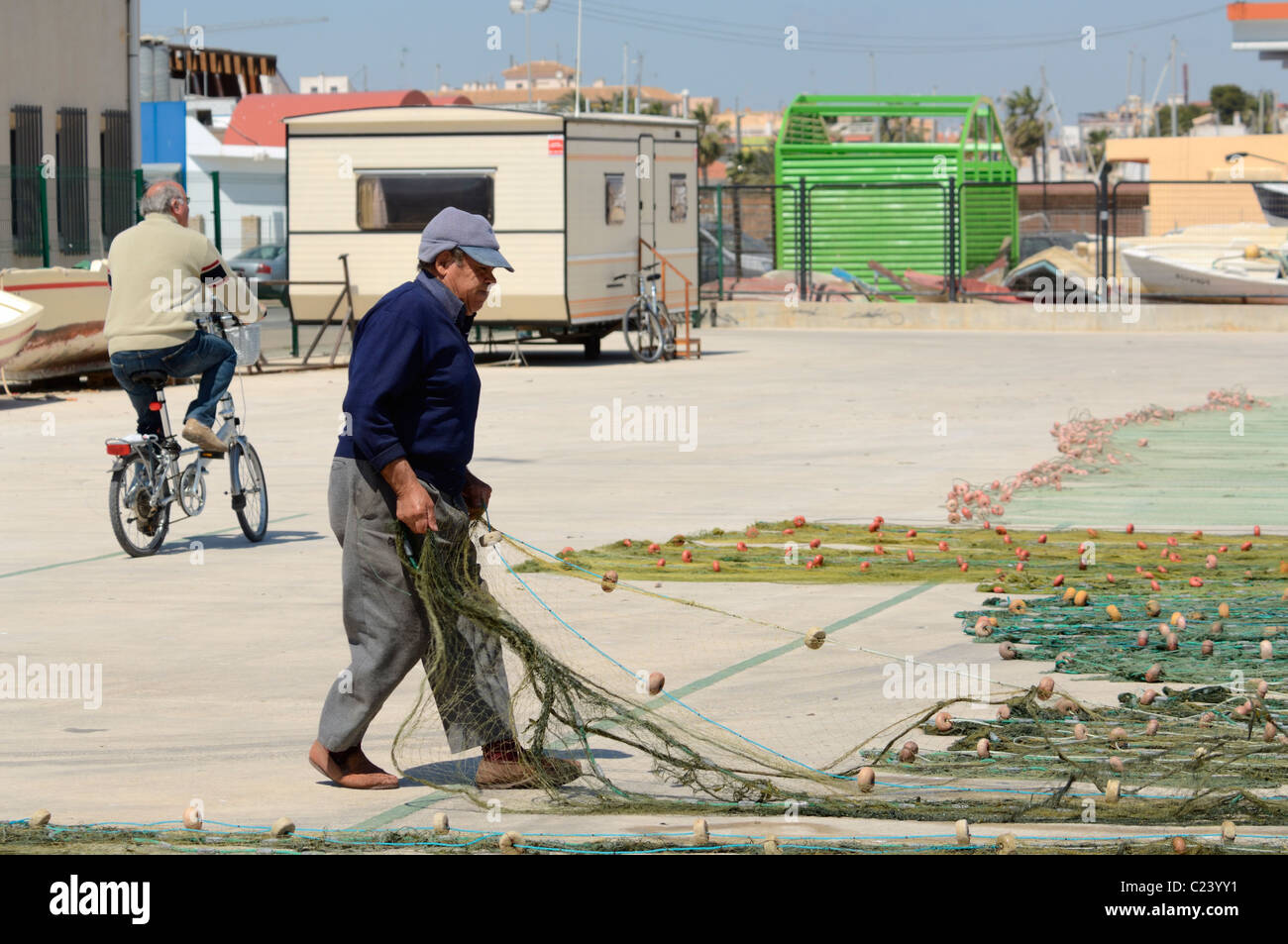 Un pêcheur a tendance à ses filets sur le quai en Méditerranée port de San Pedro del Pinatar, Murcia, Espagne. Banque D'Images