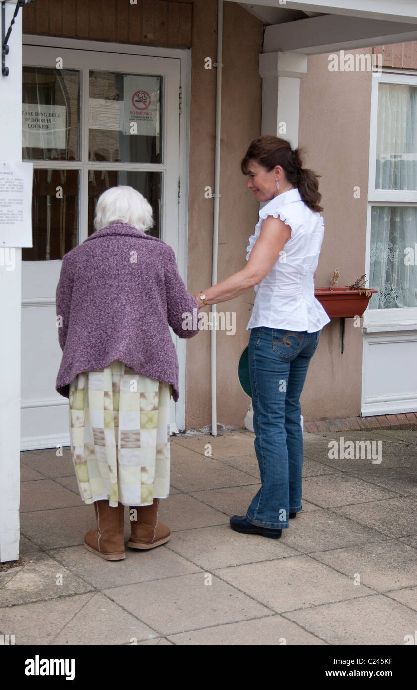 Femme marche vieille dame en maison de soins infirmiers Banque D'Images