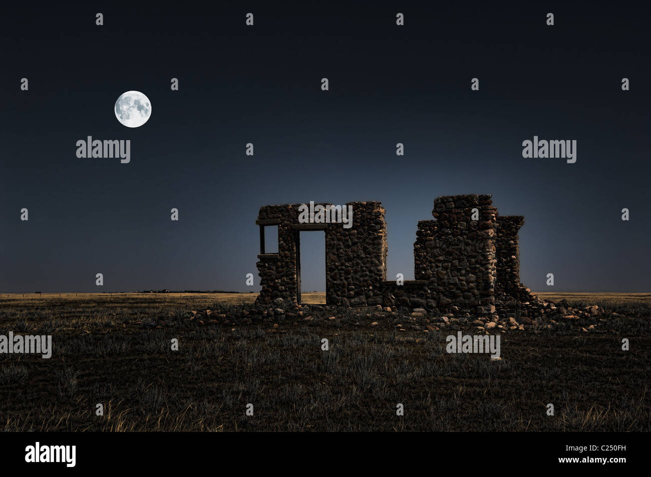 Une image surréaliste des ruines d'une ancienne ferme en pierre de nuit avec la lune en arrière-plan. Banque D'Images