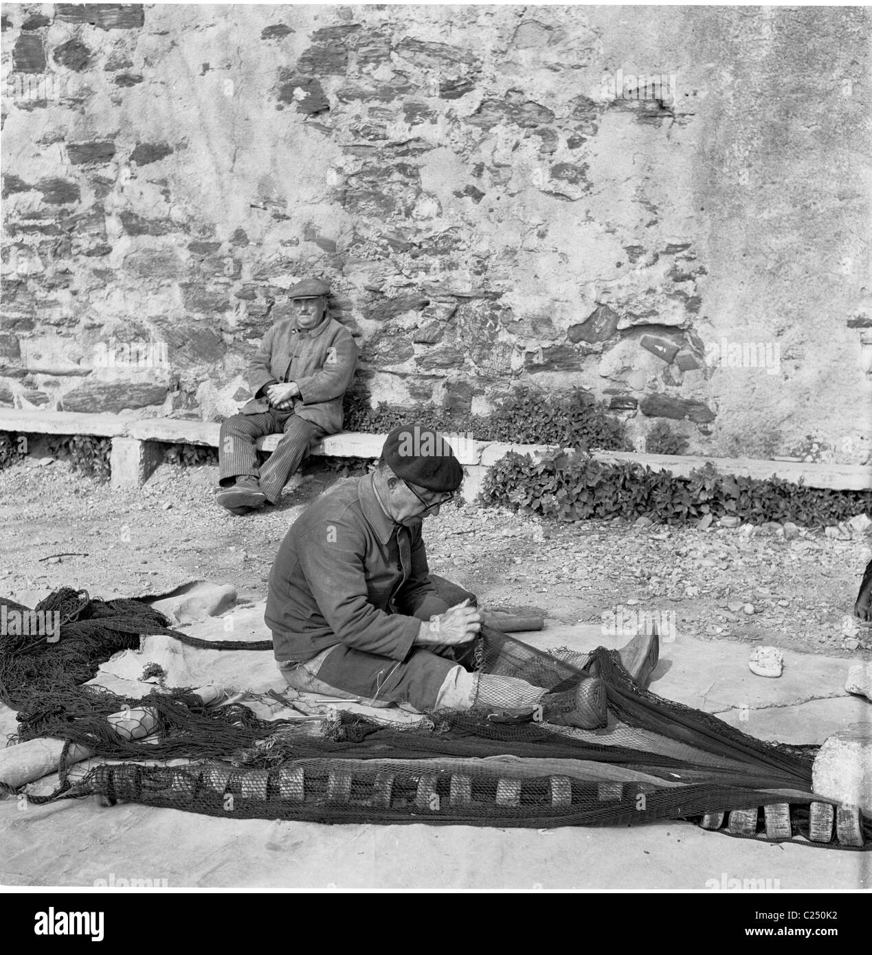 Années 1950, France. De pêcheur réparant son filet à Collioures dans cette photographie historique par J Allan l'argent comptant. Banque D'Images