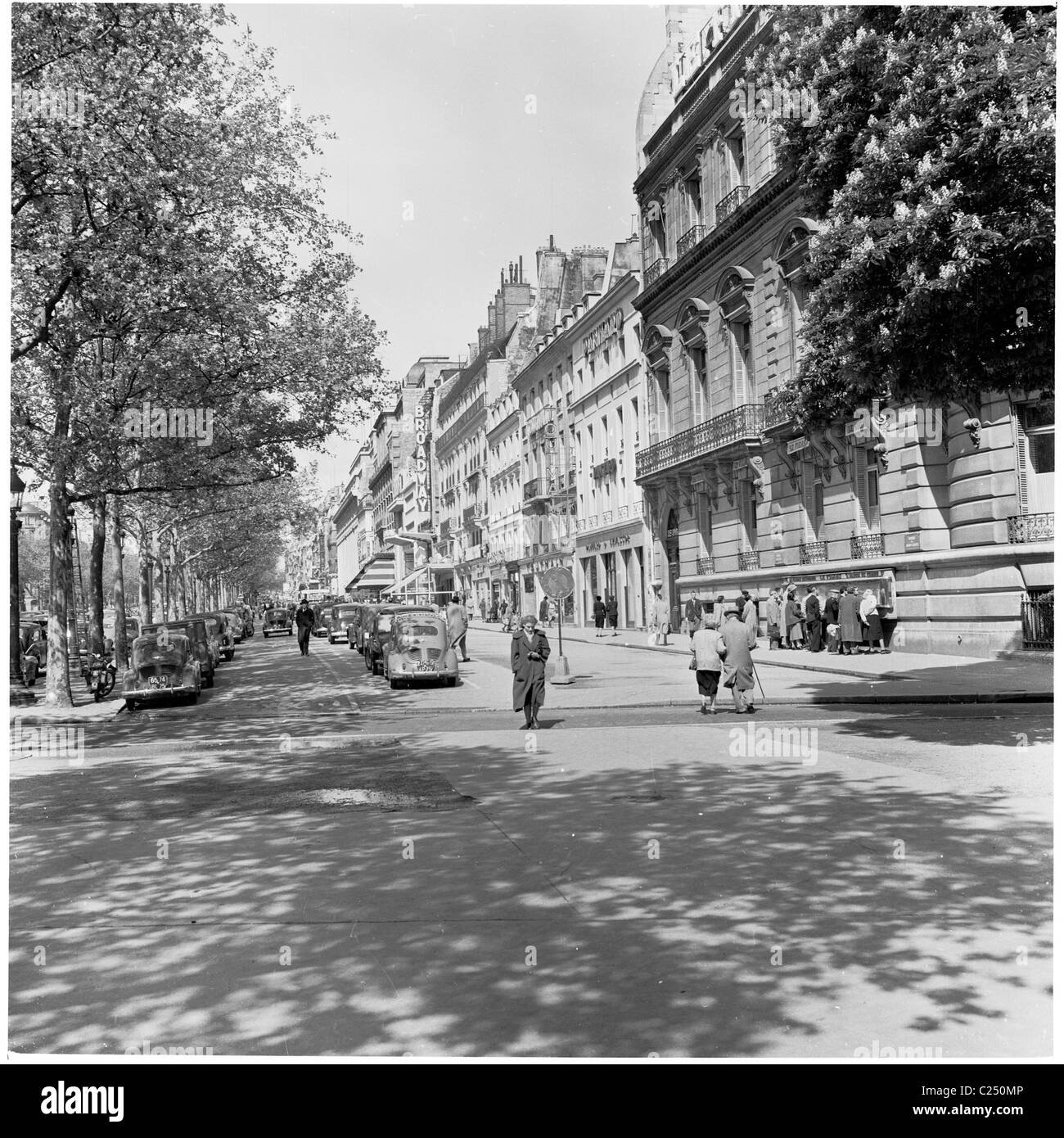 1950s, voitures garées de l'époque dans une petite rue à côté de la célèbre avenue des champs-Élysées à Paris, en France, avec quelques Parisiens passant à pied. Banque D'Images