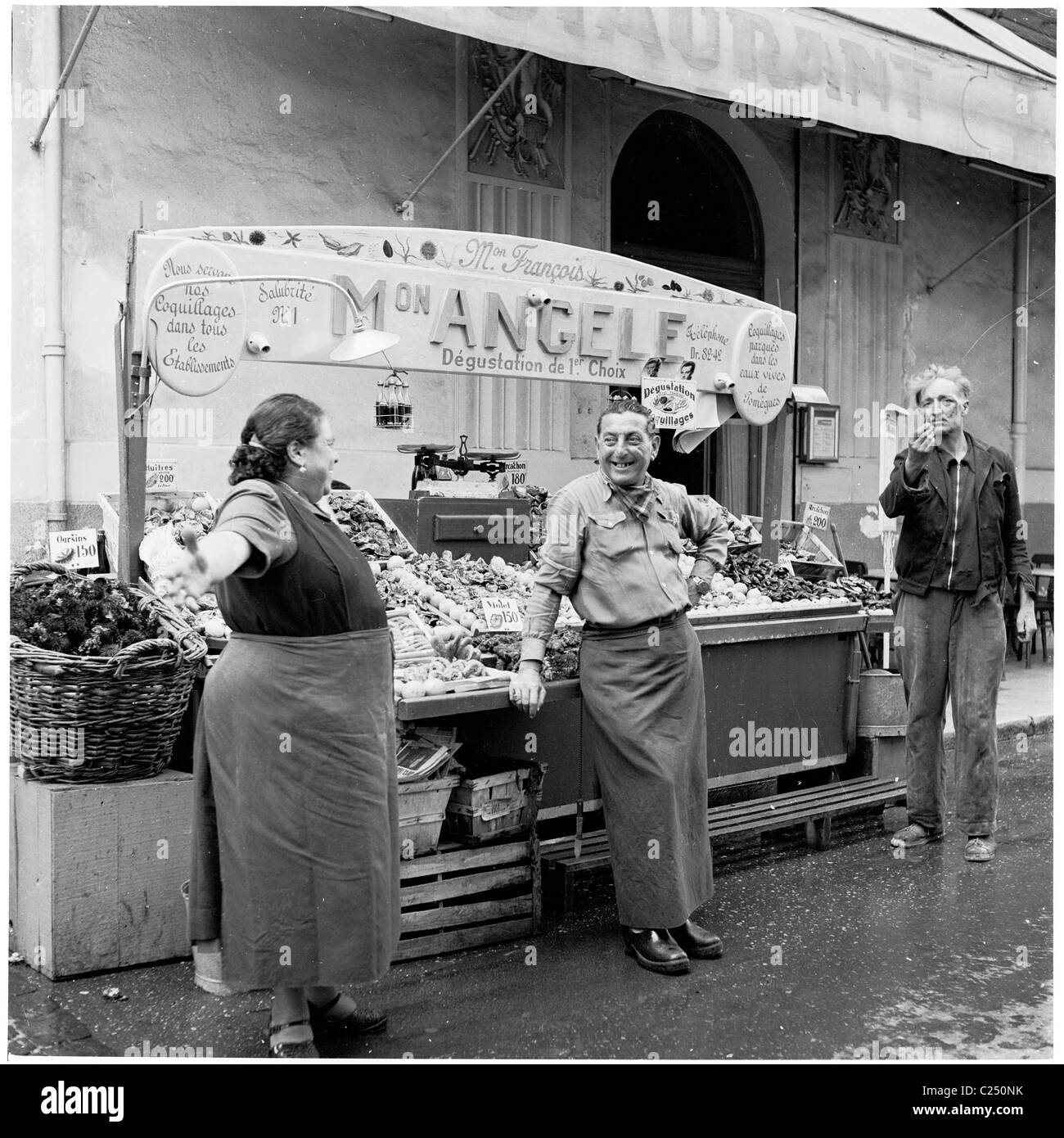 L'homme et la femme partagent une blague à l'étal de poisson, Mon Angèle, tandis qu'un mendiant clics ses doigts, au Vieux Port à Marseille. Banque D'Images