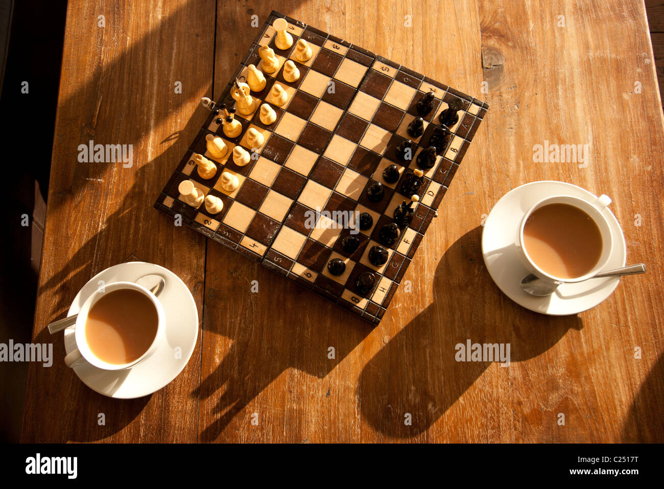 Jeu d'échecs figurant sur une table de salon avec deux tasses de thé. Banque D'Images Jeu d'échecs figurant sur une table de salon avec deux tasses de thé. Banque D'Images