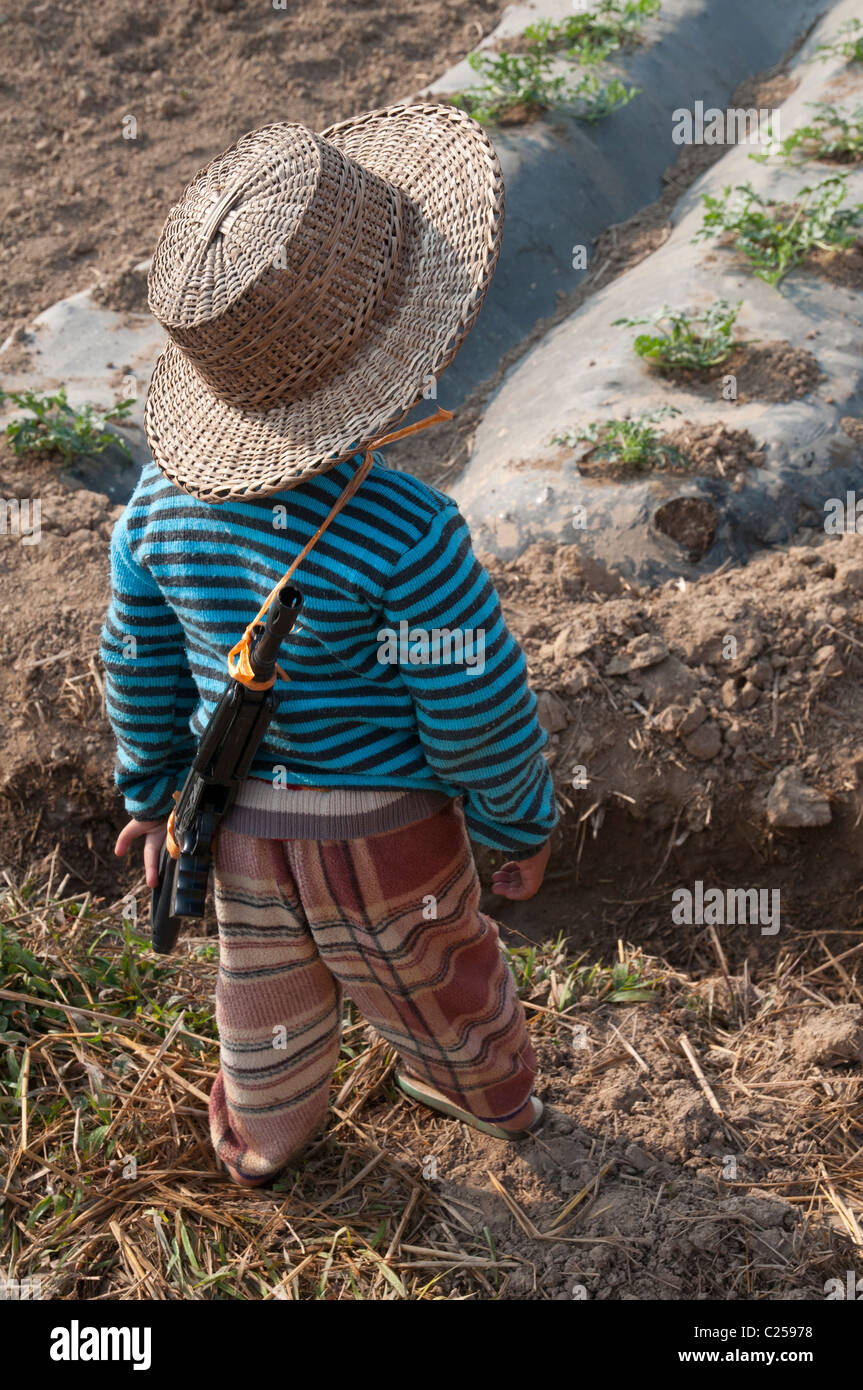 Enfant avec pistolet jouet en champ. Hsipaw. Le nord de l'État Shan. Myanmar Banque D'Images