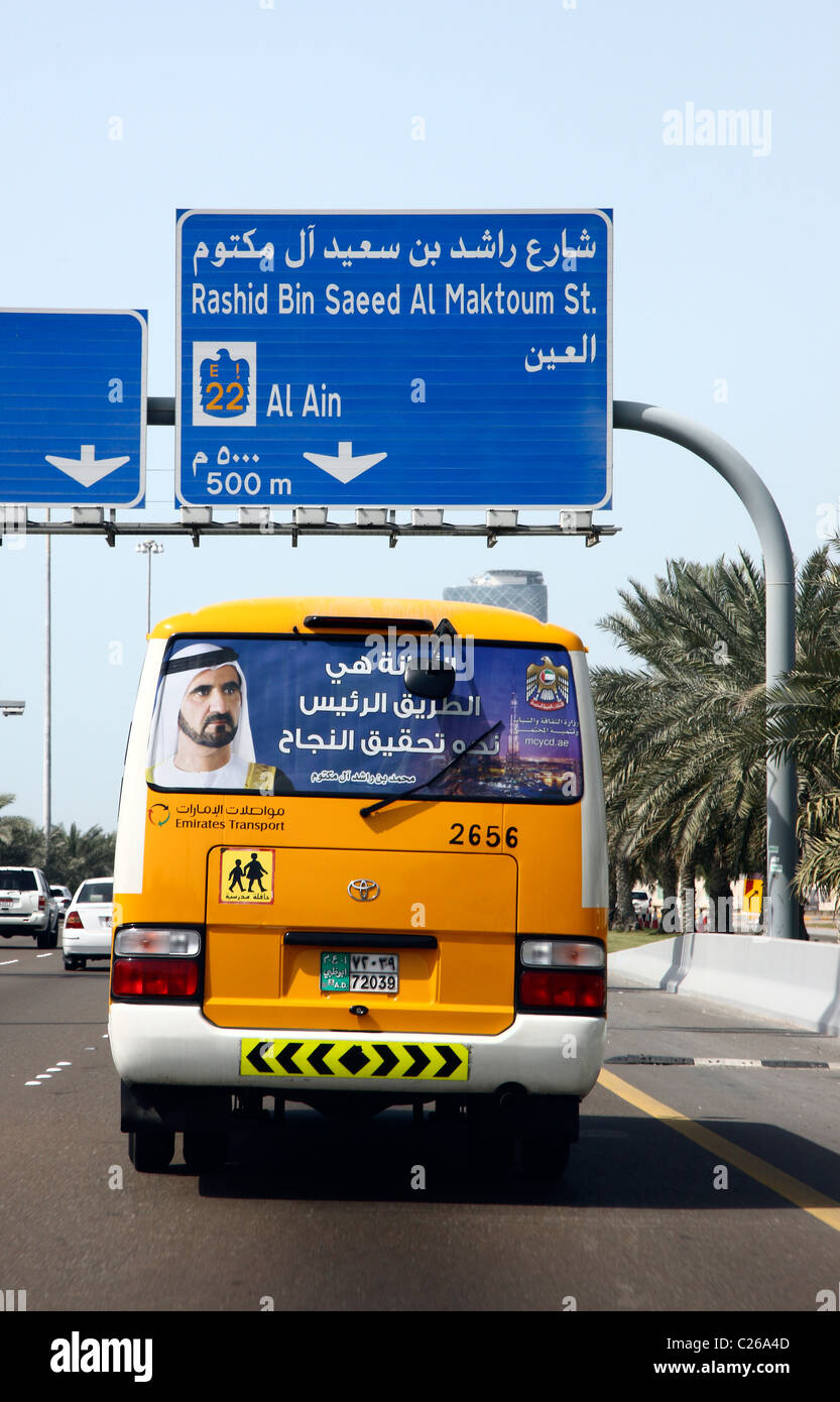 Le trafic, d'autobus scolaires, avec portrait de Muhammad bin Raschid Al Maktum, gouverneur de Dubaï. Abu Dhabi, Émirats Arabes Unis Banque D'Images