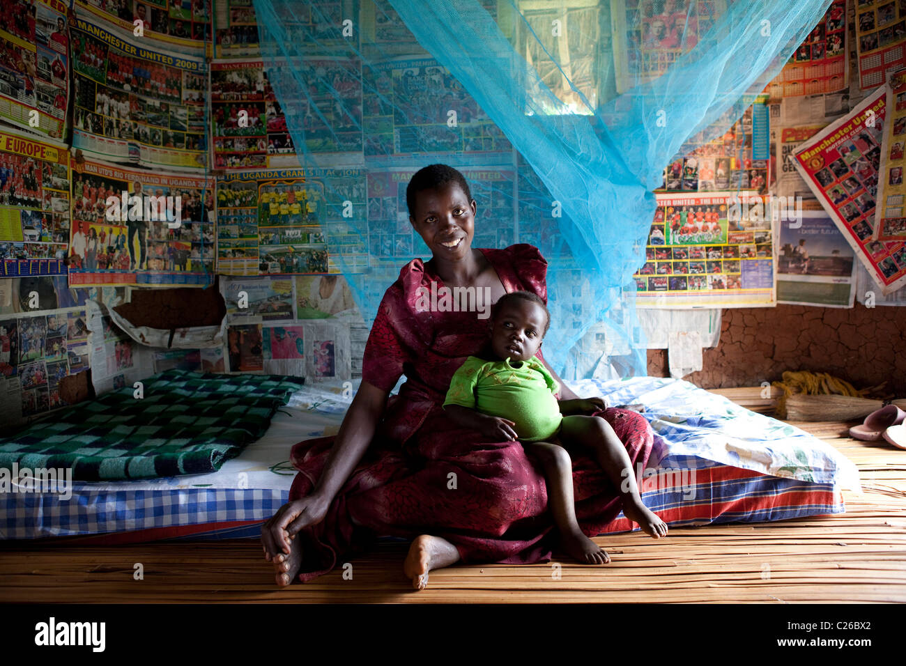 Une femme africaine et son bébé-garçon. La mère a pendu sa moustiquaire dans leur chambre à coucher Banque D'Images