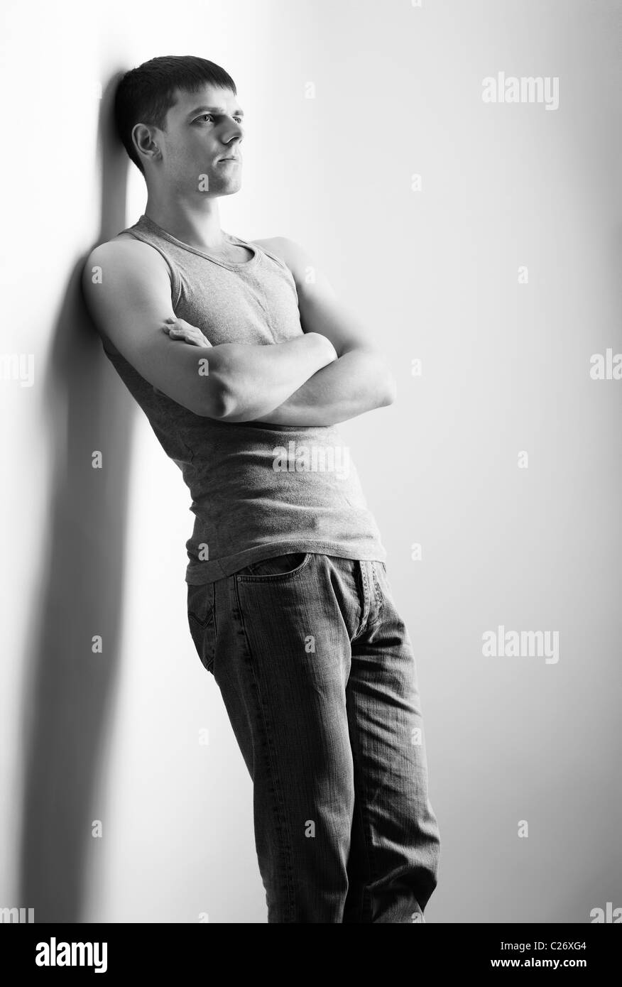 Portrait of young handsome Guy Brunet en jeans et maillot de posing sur gris Banque D'Images