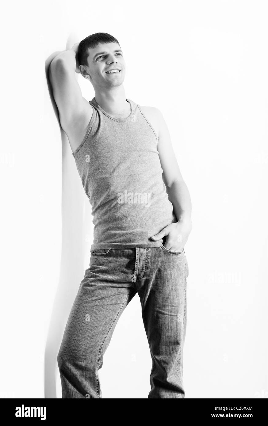 Portrait of young handsome Guy Brunet en jeans et maillot de posing sur gris Banque D'Images