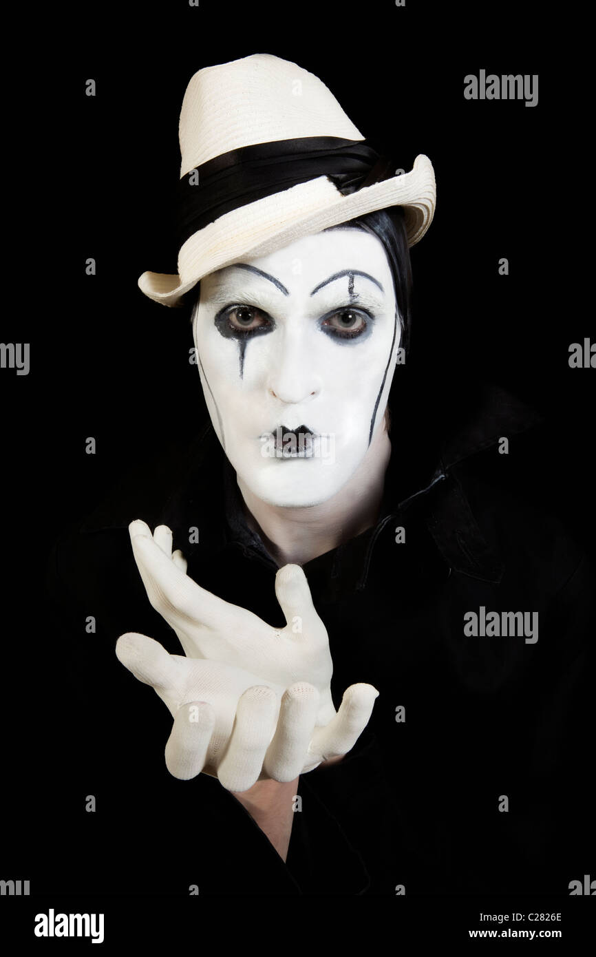 Le visage et les mains de mime avec maquillage sombre sur fond noir Banque D'Images