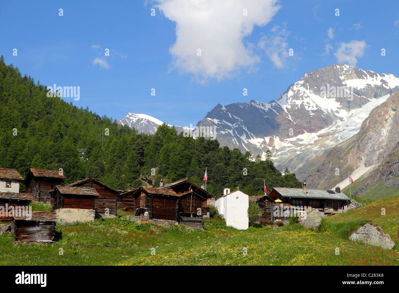 Village de maisons en bois couvertes de toits en pierre en face de la forêt et Hugh young transalpins, Suisse, Valais Banque D'Images