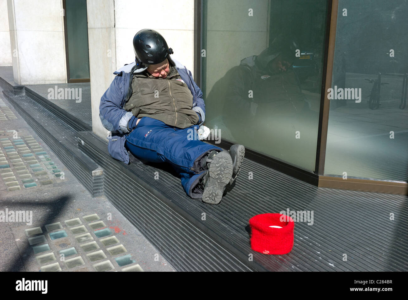 Homme endormi sans-abri mendier à l'extérieur d'un bureau à proximité de Piccadily Circus. Banque D'Images