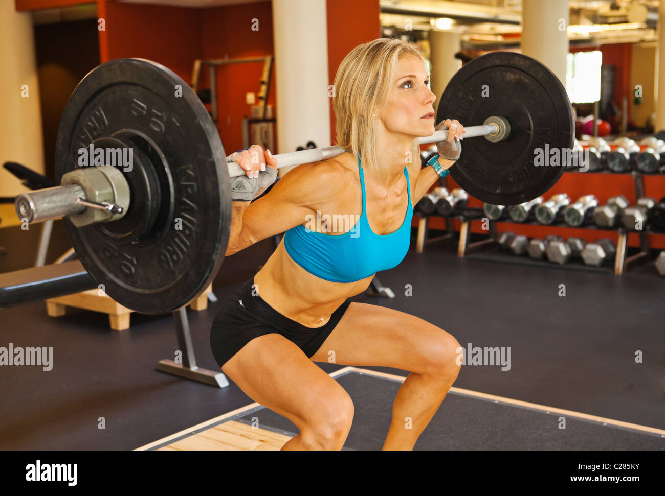 Une bonne forme physique femme s'accroupit dans un club de salle de musculation. Banque D'Images