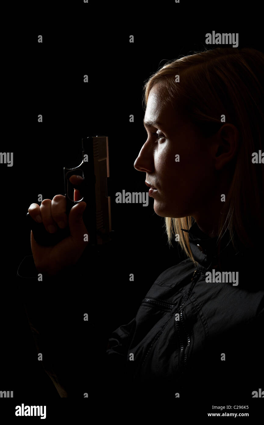Woman holding gun dans le noir Banque D'Images