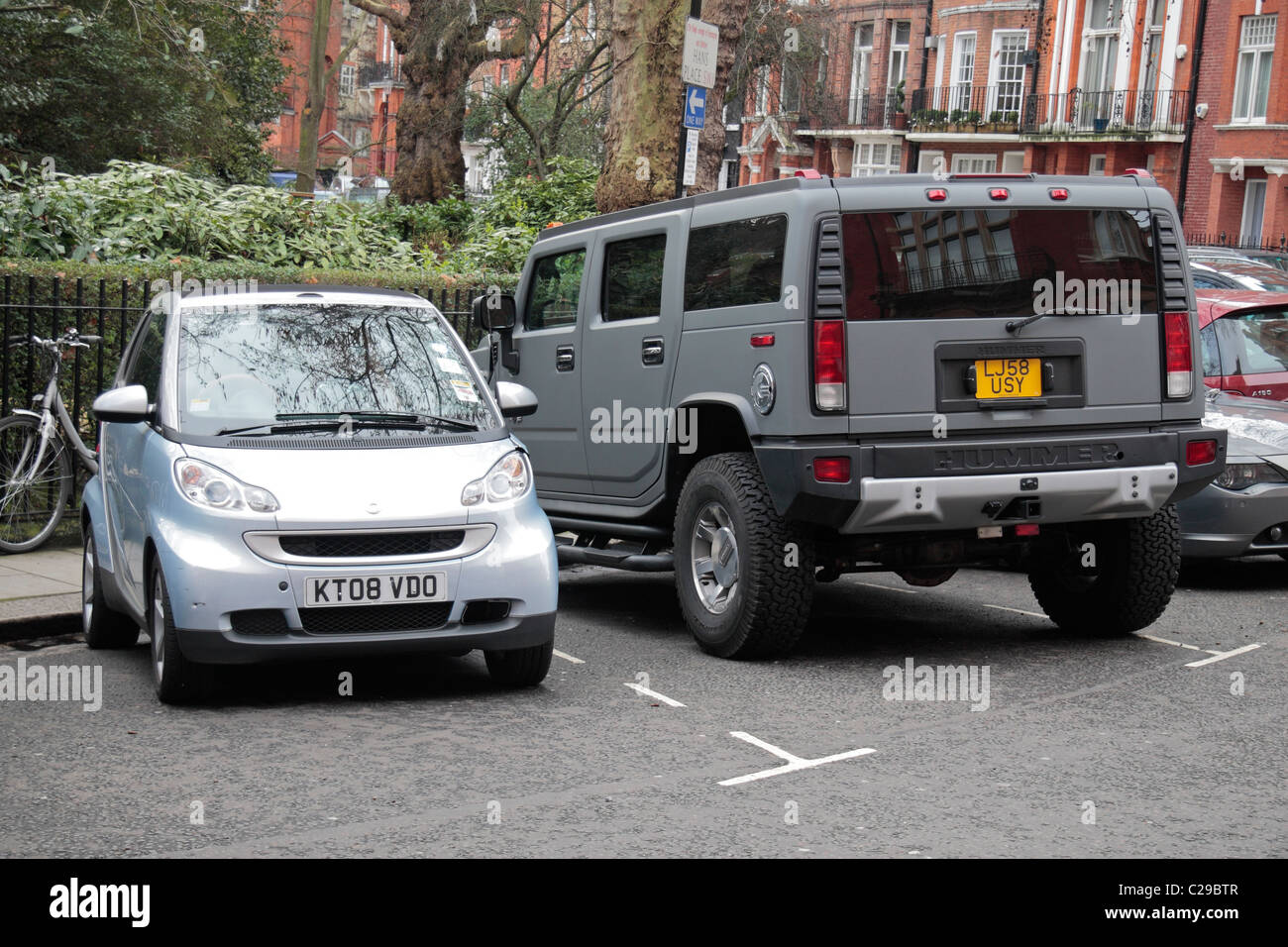 Une petite voiture garée à côté d'une puce d'énormes Hummer GM dans Hans Place, Kensington et Chelsea, London, UK. Banque D'Images