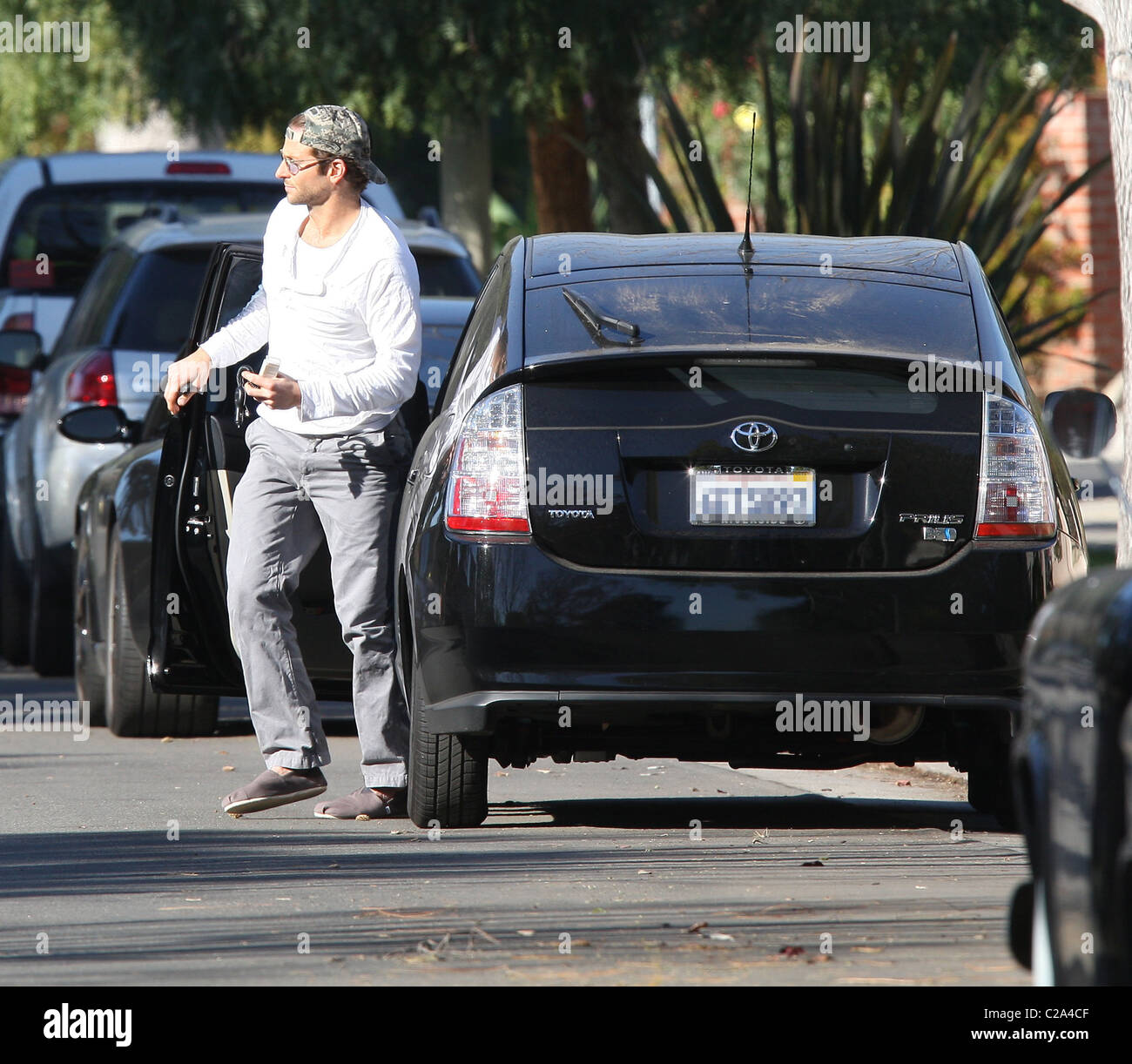 Bradley Cooper arrive à la maison dans sa voiture Toyota Prius, portant une  casquette et des chaussures type sleeper et teinte bleue Photo Stock - Alamy