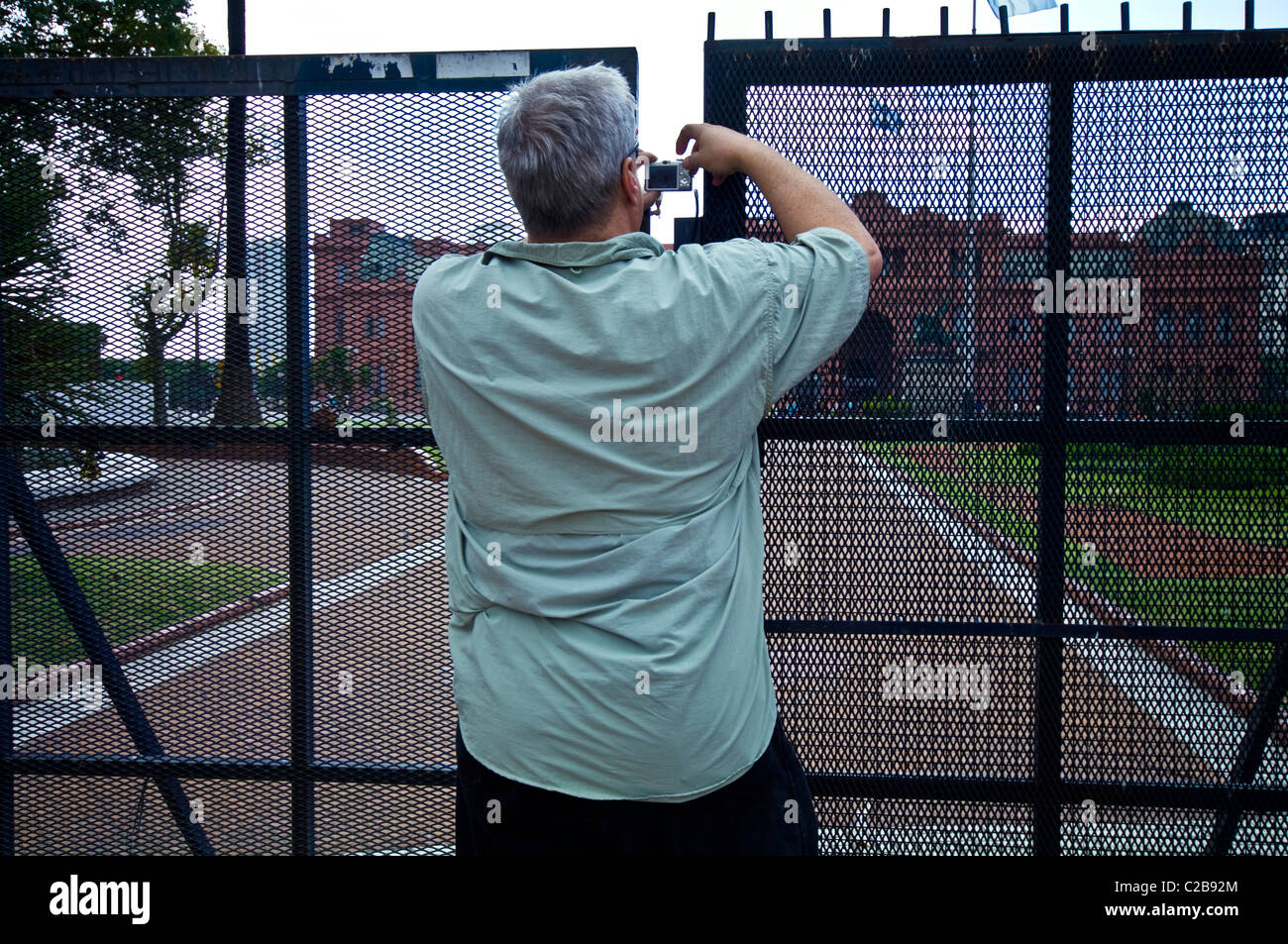 Un touriste photographie la Casa Rosada à travers une barrière de sécurité en acier. Banque D'Images