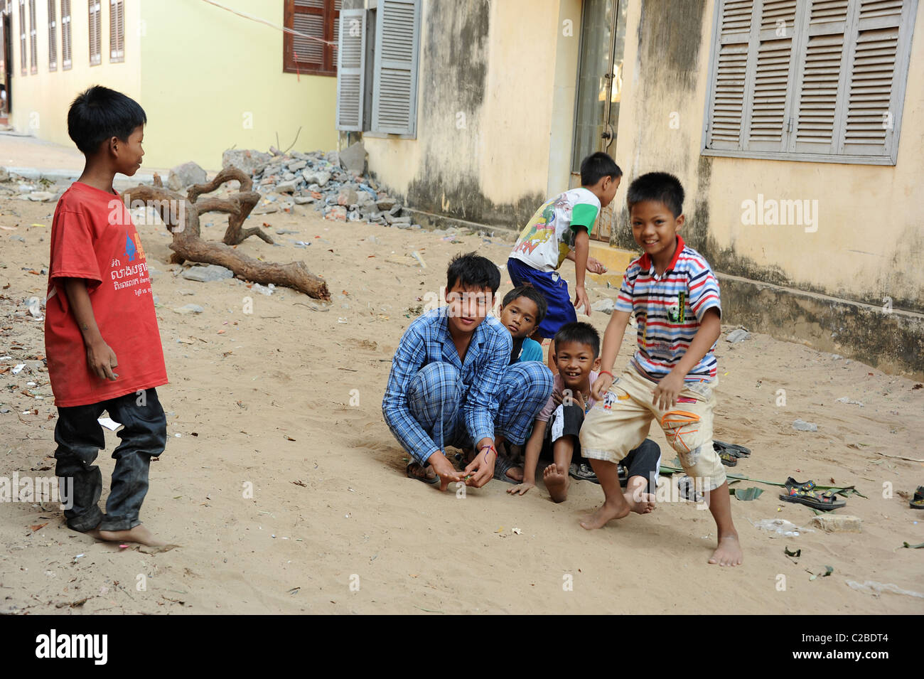 Les garçons jouer avec des billes dans le sable. Ounalom temple de Phnom Penh, Cambodge. Banque D'Images