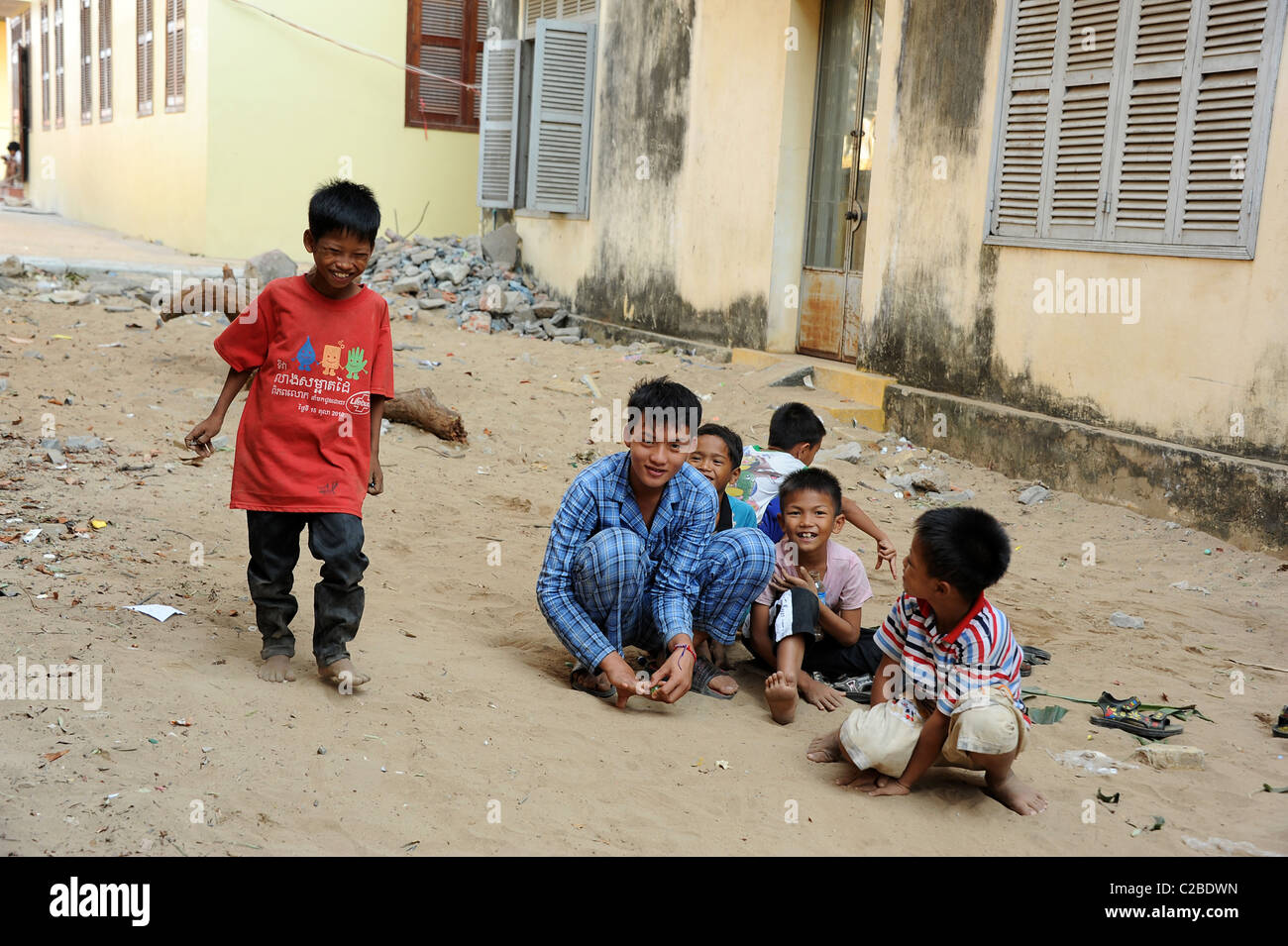 Les garçons jouer avec des billes dans le sable. Ounalom temple de Phnom Penh, Cambodge. Banque D'Images