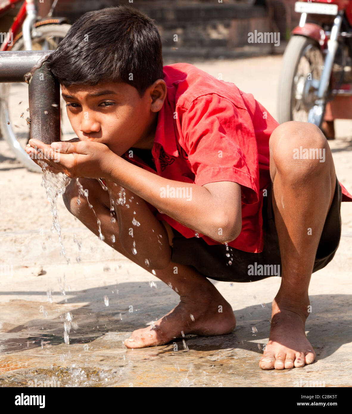 Un garçon de boissons dans une pompe à eau dans Valsang Village Maharashtra Inde Banque D'Images