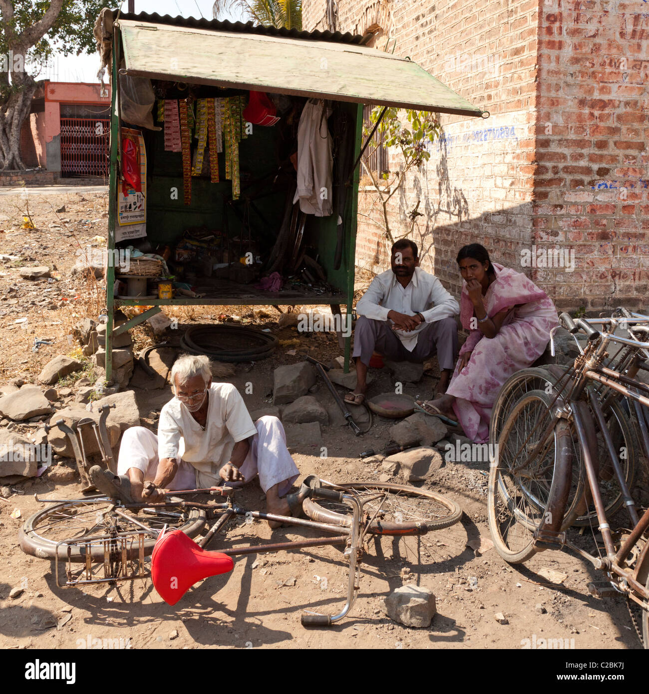 Un vieil homme de réparation de vélos indiens travaillant par son échoppe dans Valsang Village Maharashtra Inde Banque D'Images