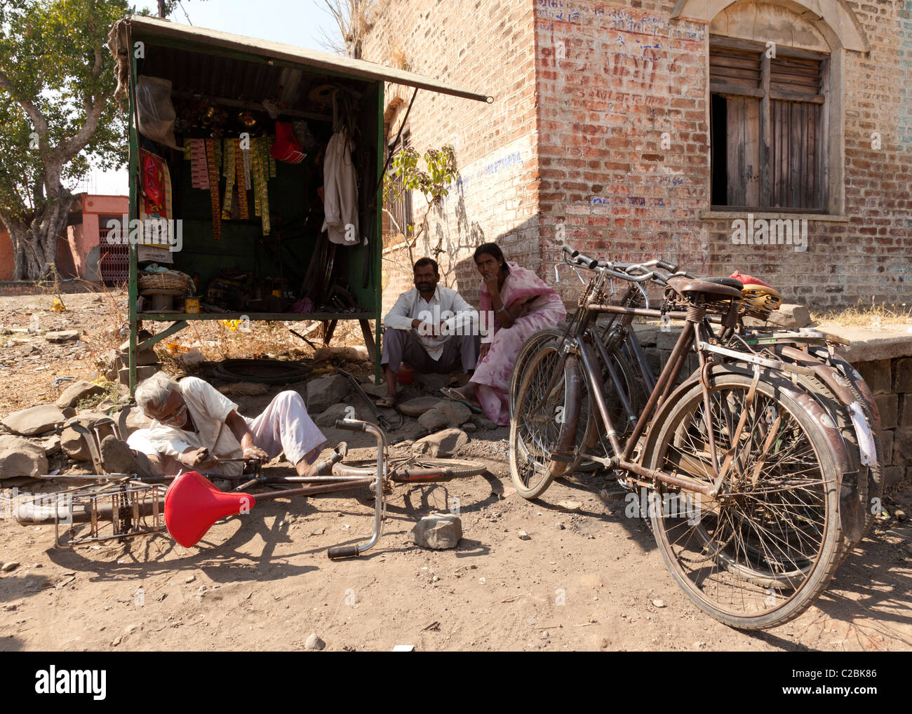 Un vieil homme de réparation de vélos indiens travaillant par son échoppe dans Valsang Village Maharashtra Inde Banque D'Images