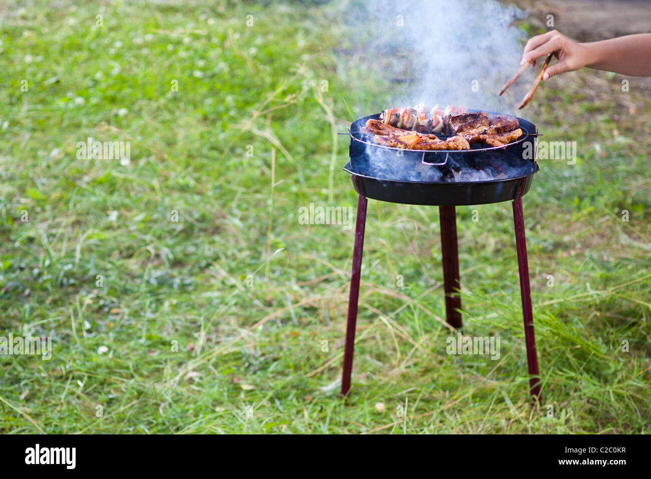 Tourner à la main sur le barbecue grill avec pinces avec belle de fumée visible. Banque D'Images