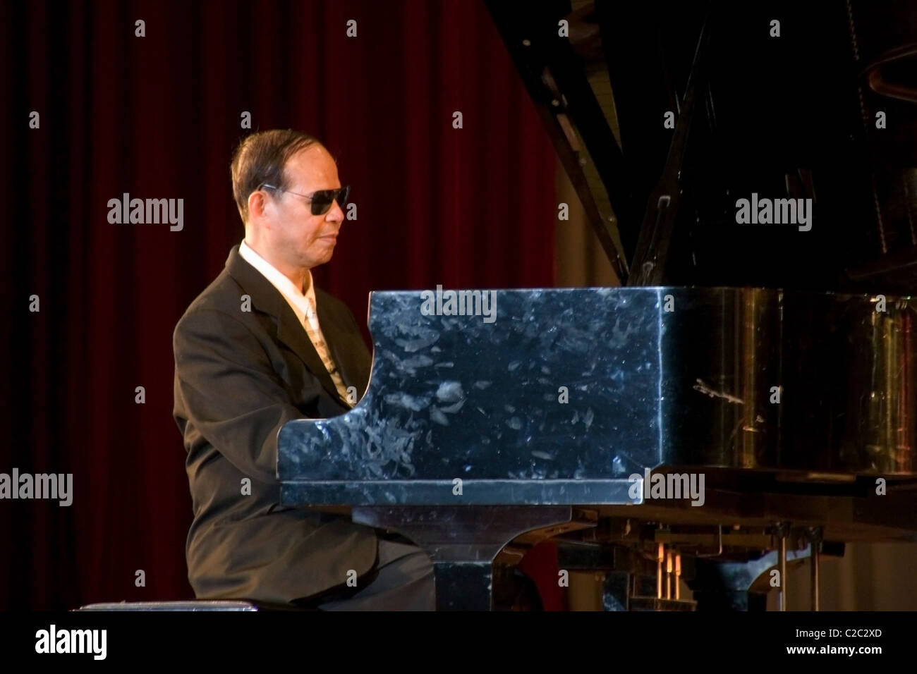 Une mobilité aveugles (sans vision) Asian man wearing sunglasses joue un grand piano à Vientiane, au Laos. Banque D'Images