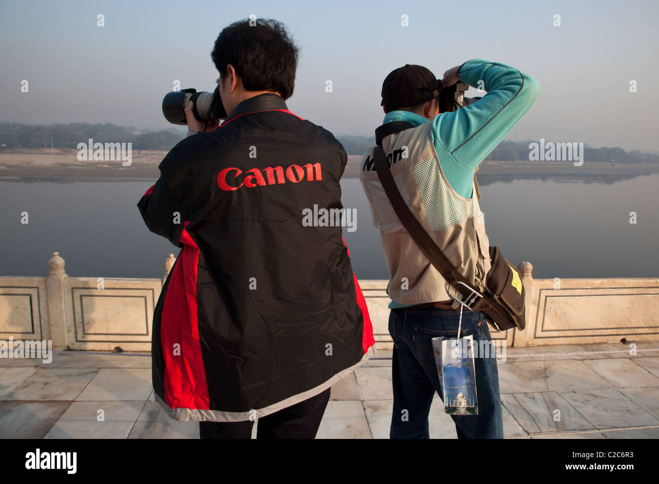 Les touristes chinois portant des gilets Canon et Nikon de prendre des photos de la rivière Yamuna Taj Mahal à Agra, Inde. Banque D'Images