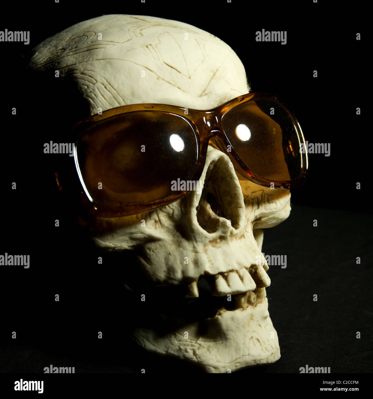 Un crâne en céramique portant des lunettes de soleil bon marché. Banque D'Images