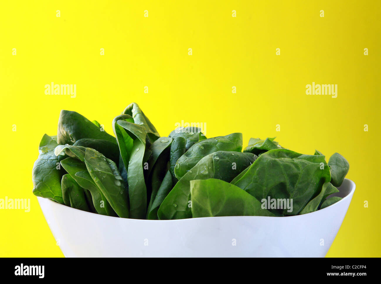 Épinards frais vert sur une assiette blanche Banque D'Images