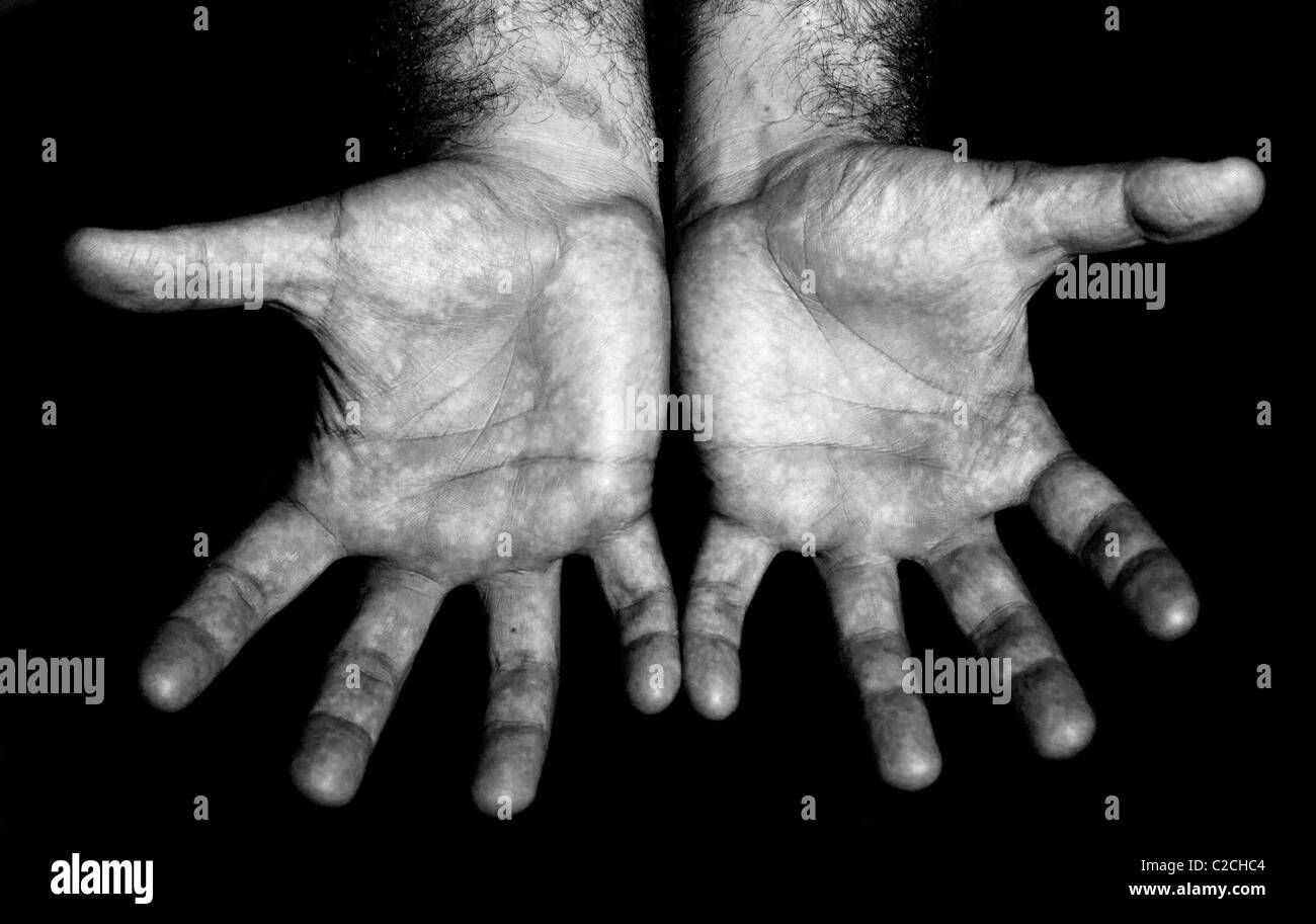 Les mains des hommes en noir et blanc sur fond noir montrant les paumes ouvertes Banque D'Images