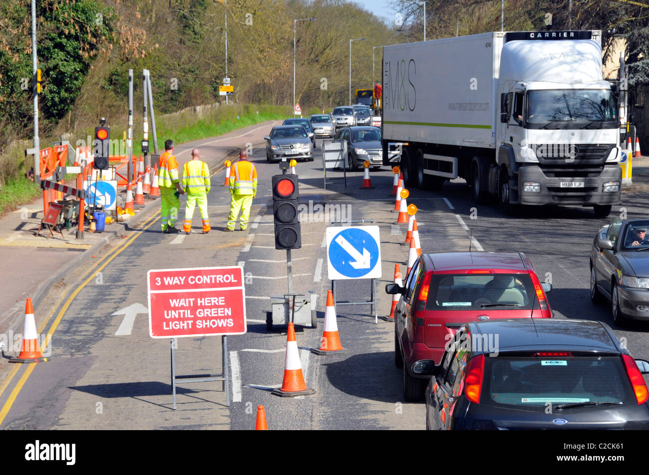 Vue d'en haut regardant vers le bas ouvriers à haute visibilité lors de travaux routiers sur la file d'attente de contrôle de feux de circulation temporaire à trois voies de véhicules Cambridge Angleterre Royaume-Uni Banque D'Images