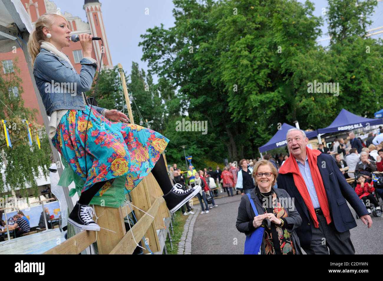 Jeune femme chanter en même temps sur une clôture en bois dans la région de Stockholm, Stockholms Lan, Suède Banque D'Images
