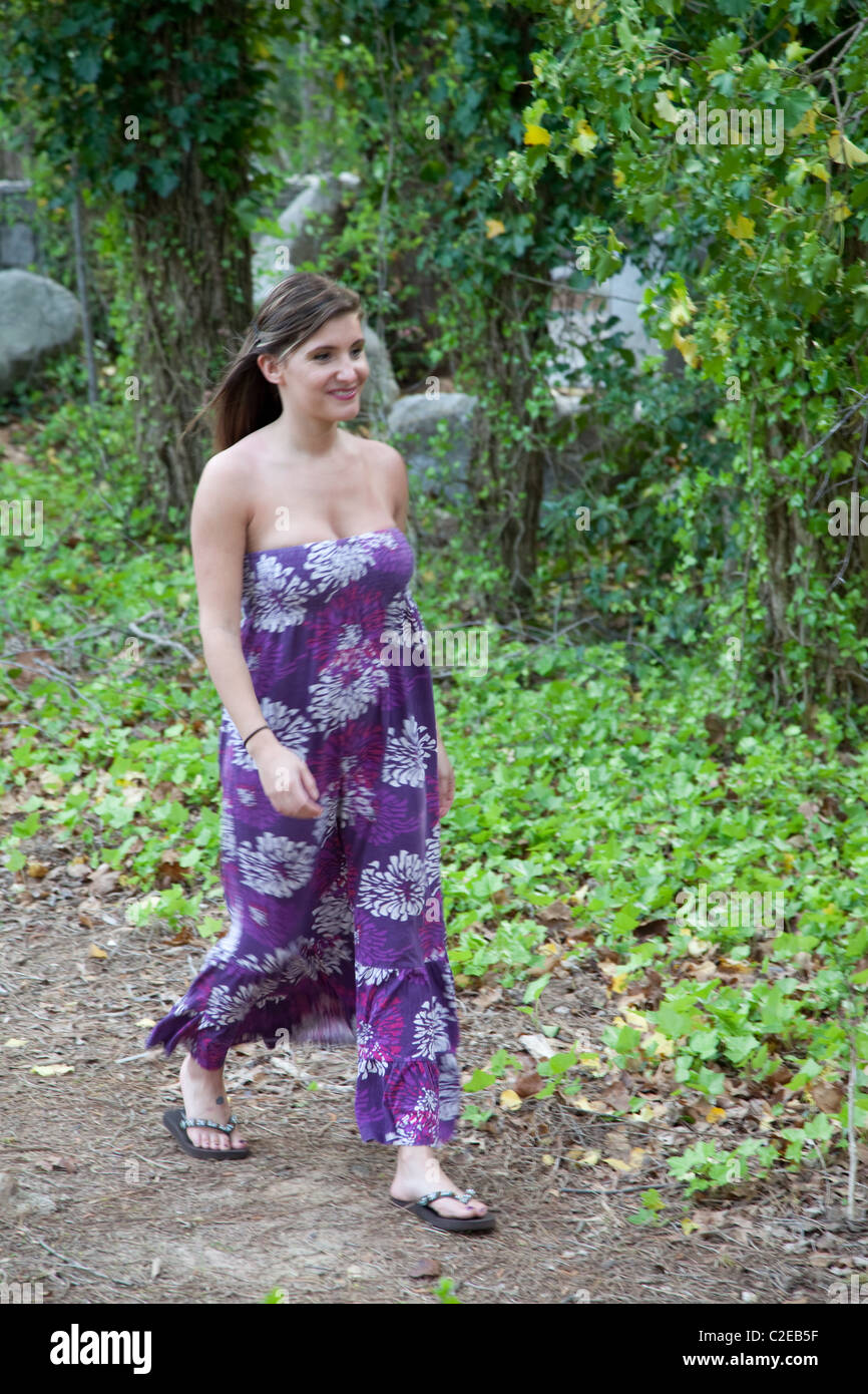 Femme charmante promenade sur un sentier à côté de certains arbres Banque D'Images