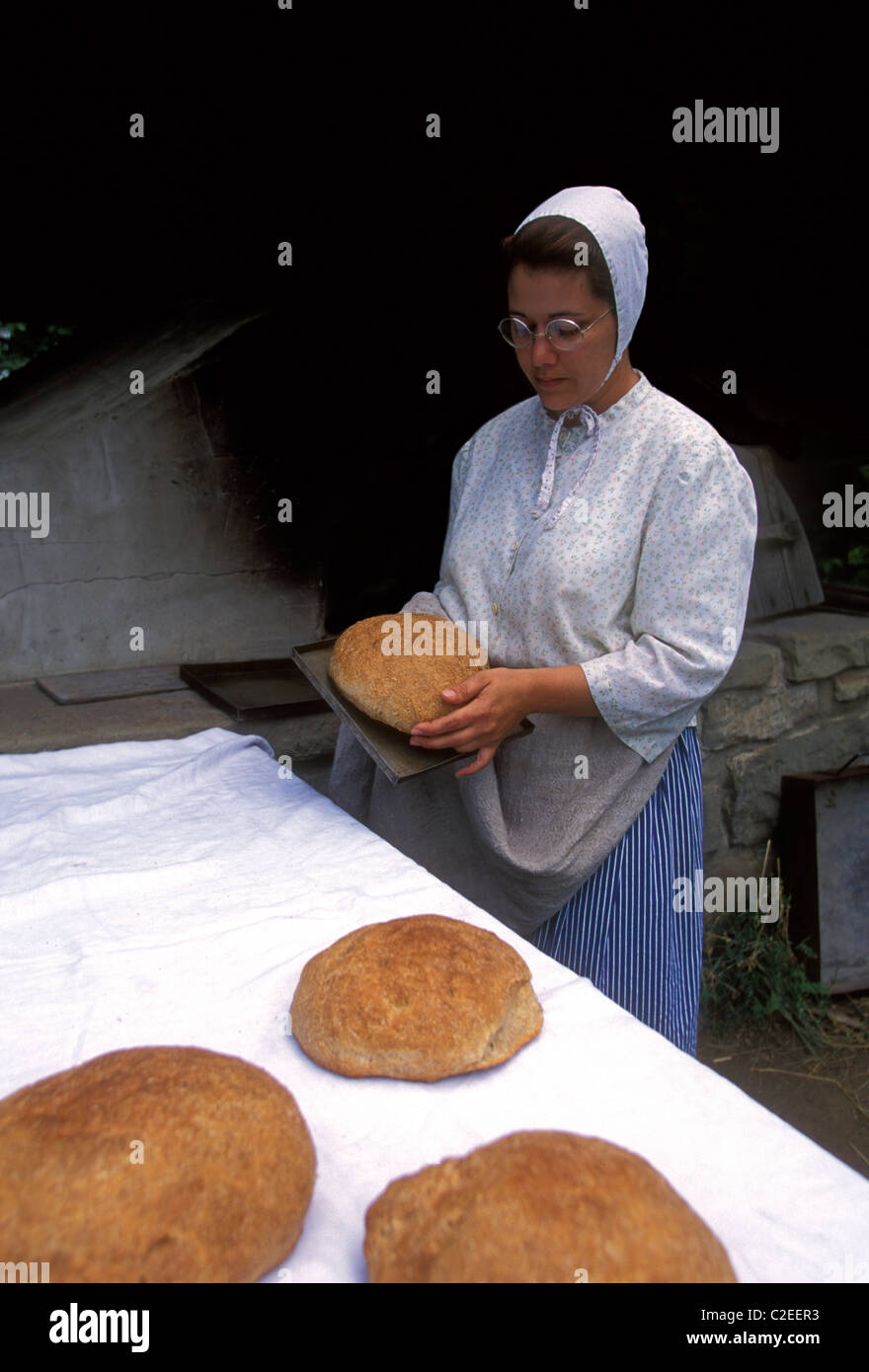 1, une femme canadienne, la période de port du costume, la cuisson du pain, le Village Historique Acadien, près de ville de Caraquet, Nouveau-Brunswick, Canada Province Banque D'Images