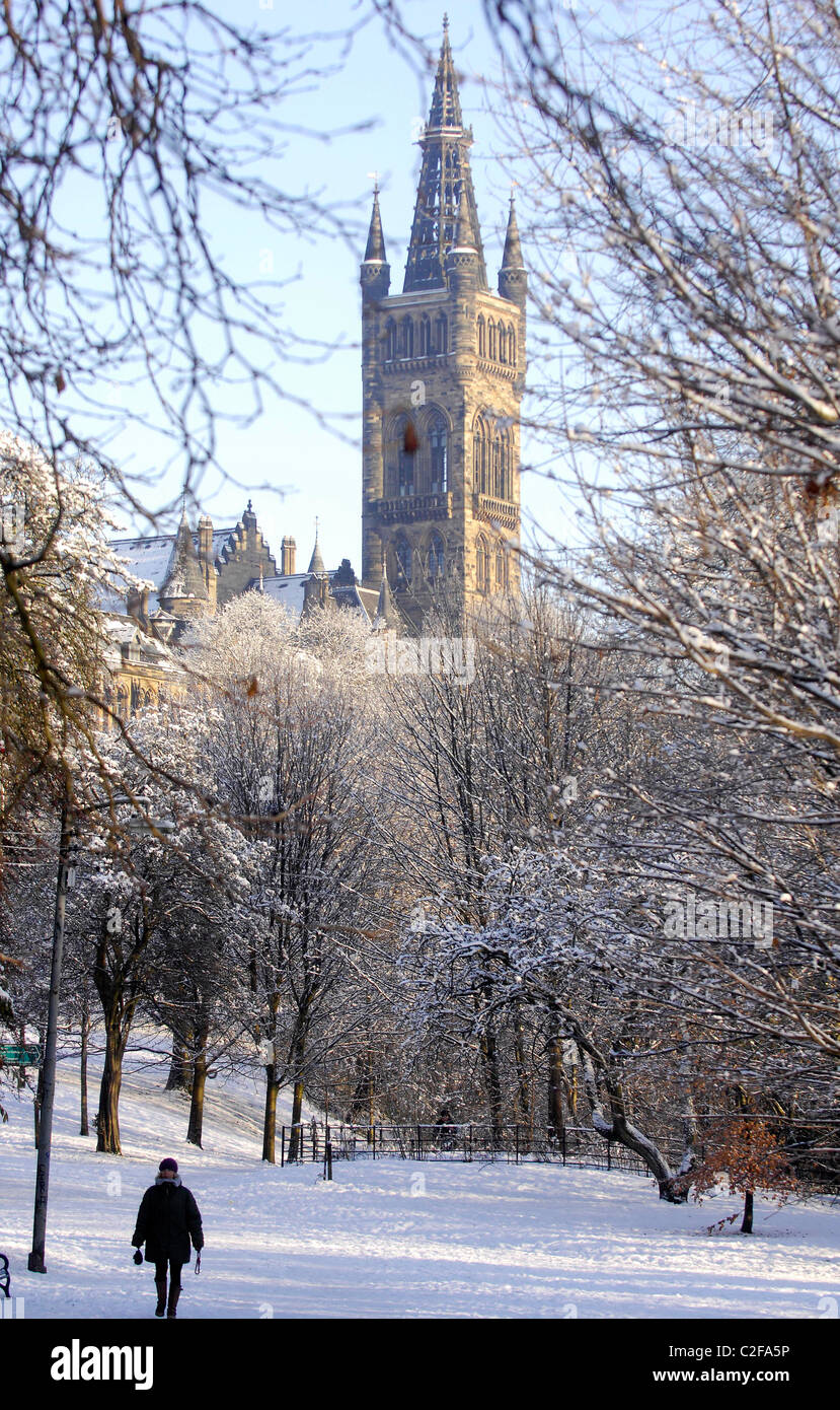 Une personne marche à travers le parc Kelvingrove à Glasgow après une importante chute de neige. L'Université de Glasgow est représenté derrière. Banque D'Images