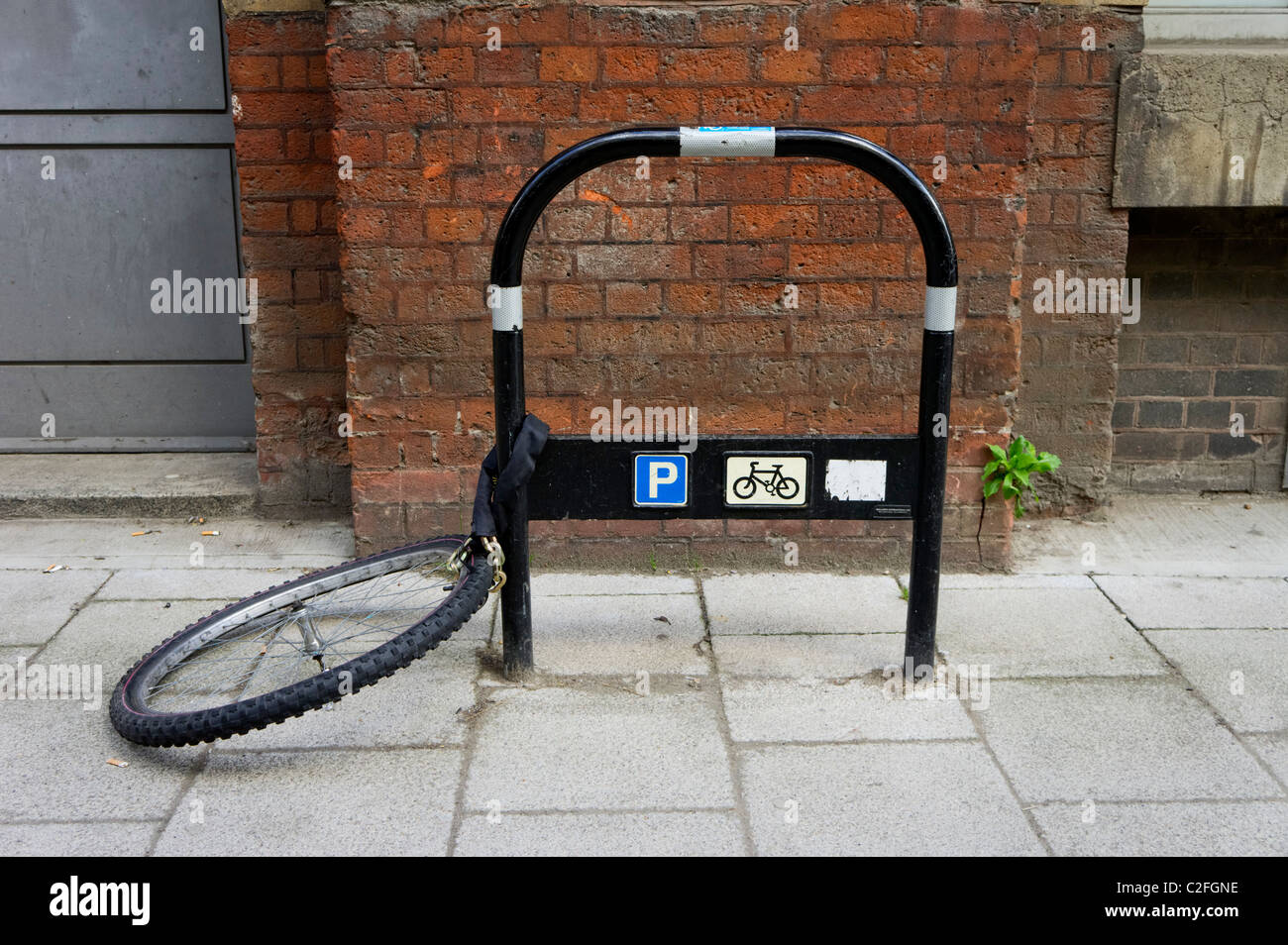 Roue de vélo enchaîné à un poste de stationnement pour vélos Banque D'Images
