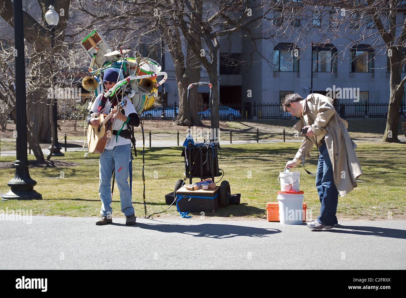 L'homme laisse un pourboire pour un musicien jouant avec une guitare et de nombreux autres instruments dans le Jardin Public de Boston Banque D'Images