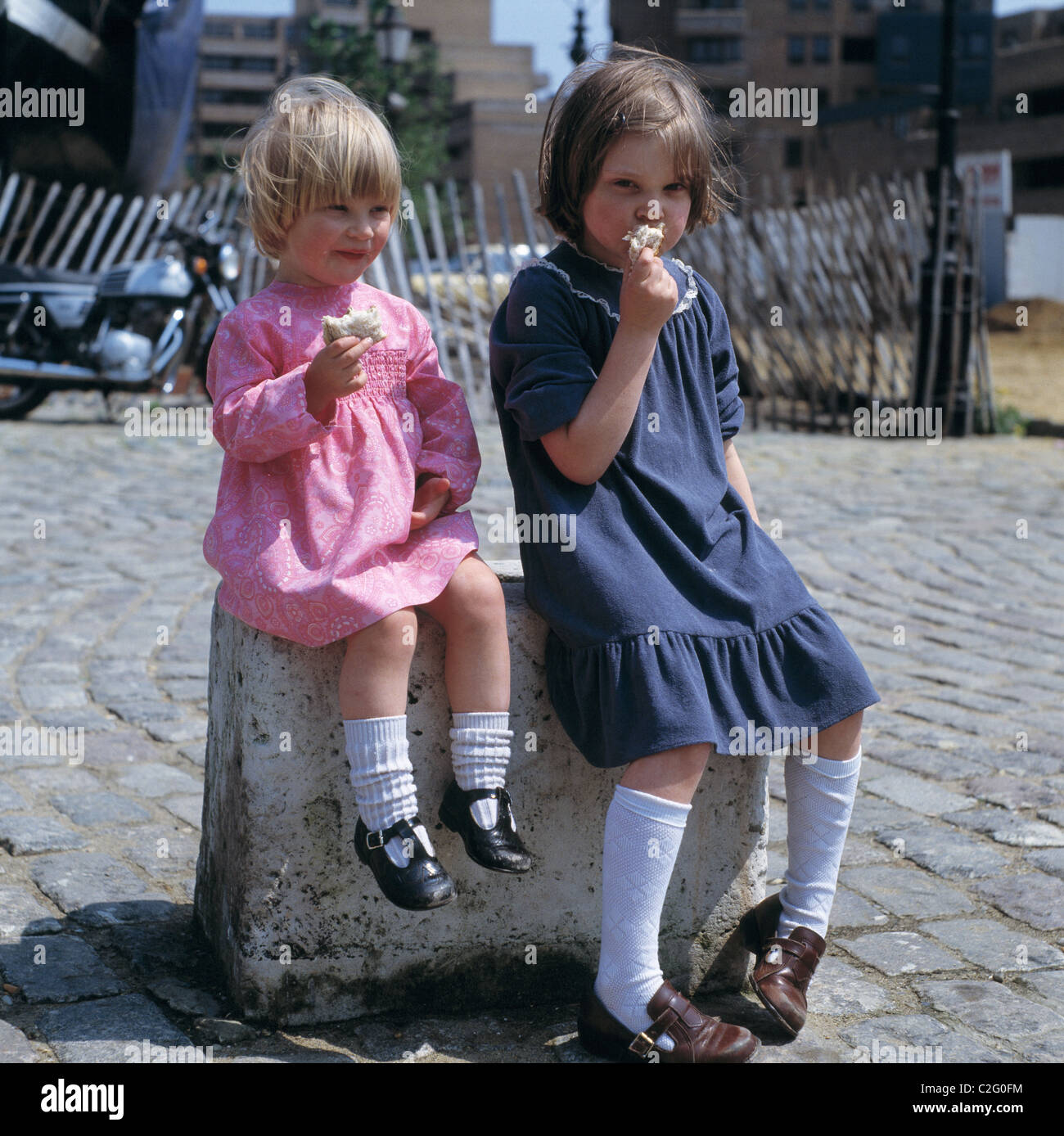 Années 70, les gens, les enfants, portrait, deux petites filles s'asseoir sur un poteau en train de manger un sandwich, âgés de 3 à 4 ans, de 5 à 8 ans, France, England, GB-LONDON Banque D'Images