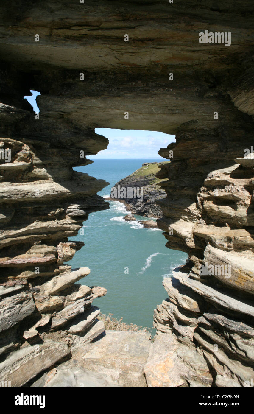 Vue sur la mer et pointe à travers une fenêtre en pierre à Tintagel, Cornwall, Angleterre Banque D'Images