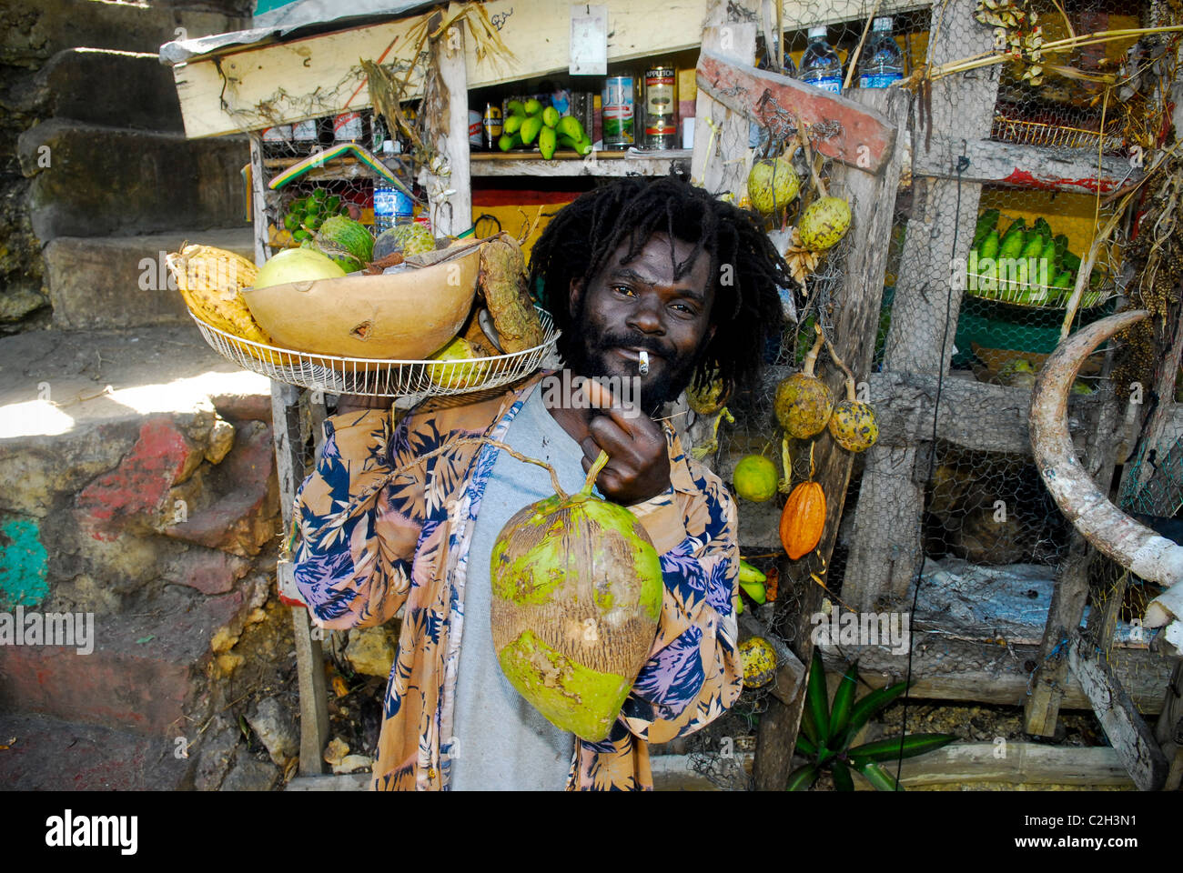Vendeur de fruits Rasta Bull affiche panier de fruits à la vente à son stand de fruits en bordure de route près de Mayfield Falls, Westmoreland, Jamaïque Banque D'Images