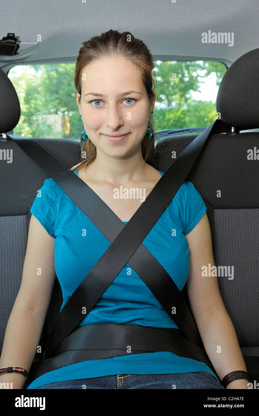 Jeune fille de 18 ans sur le siège arrière d'une voiture est retenu avec deux ceintures sear, un peu trop. Banque D'Images