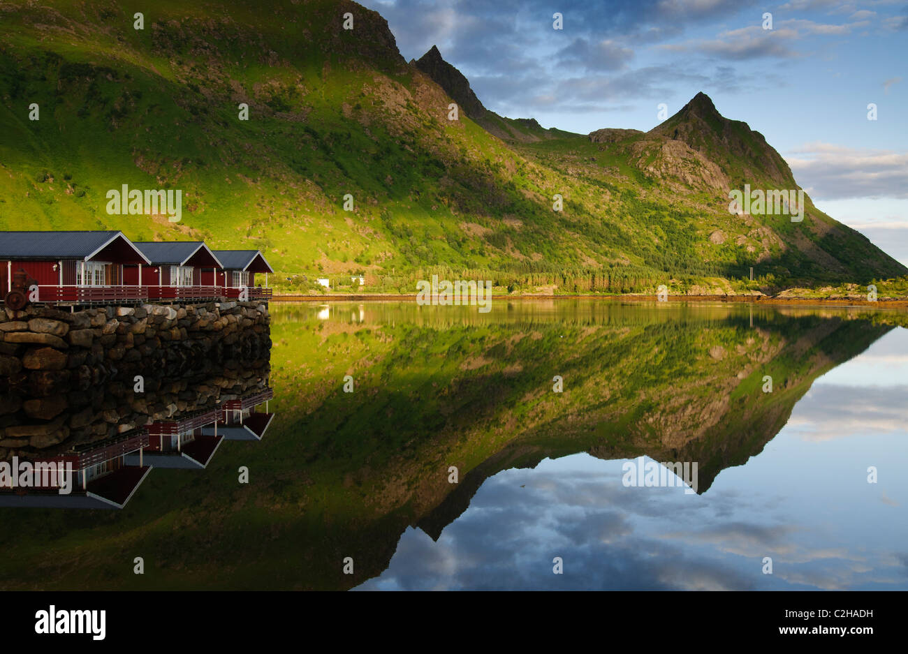 Chalets (hytter) avec des montagnes se reflétant dans l'eau, les îles Lofoten, Norvège Banque D'Images